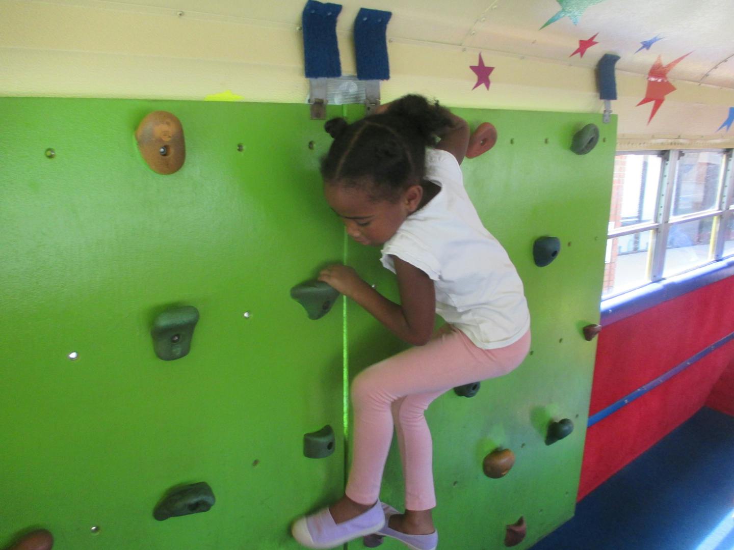 Child climbing on a green rock wall