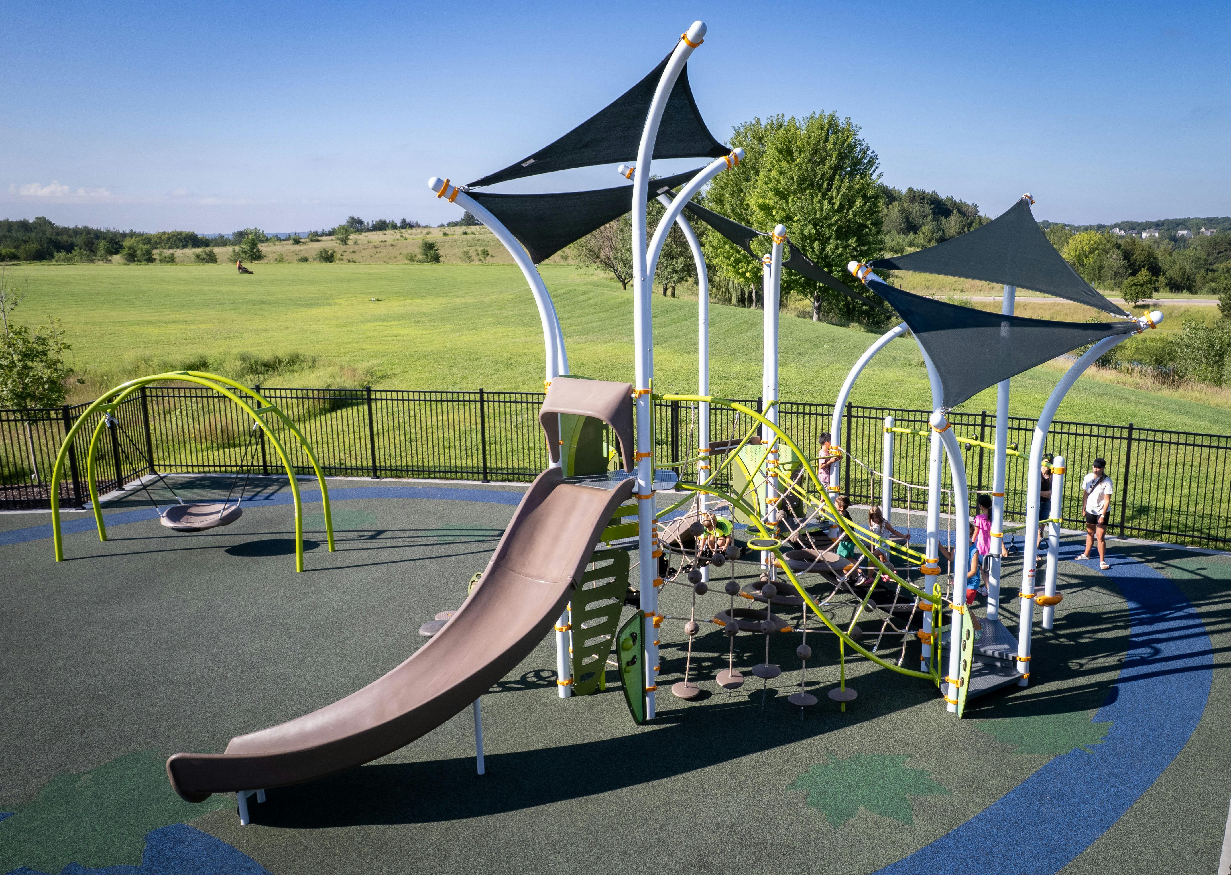Playground with slide, climbing net, and swings, with children playing