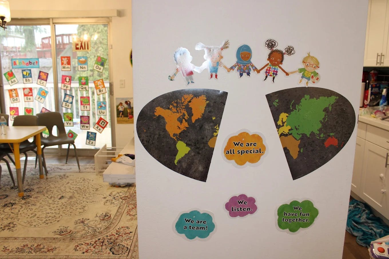 Children's artwork of paper dolls and world maps on a white wall
