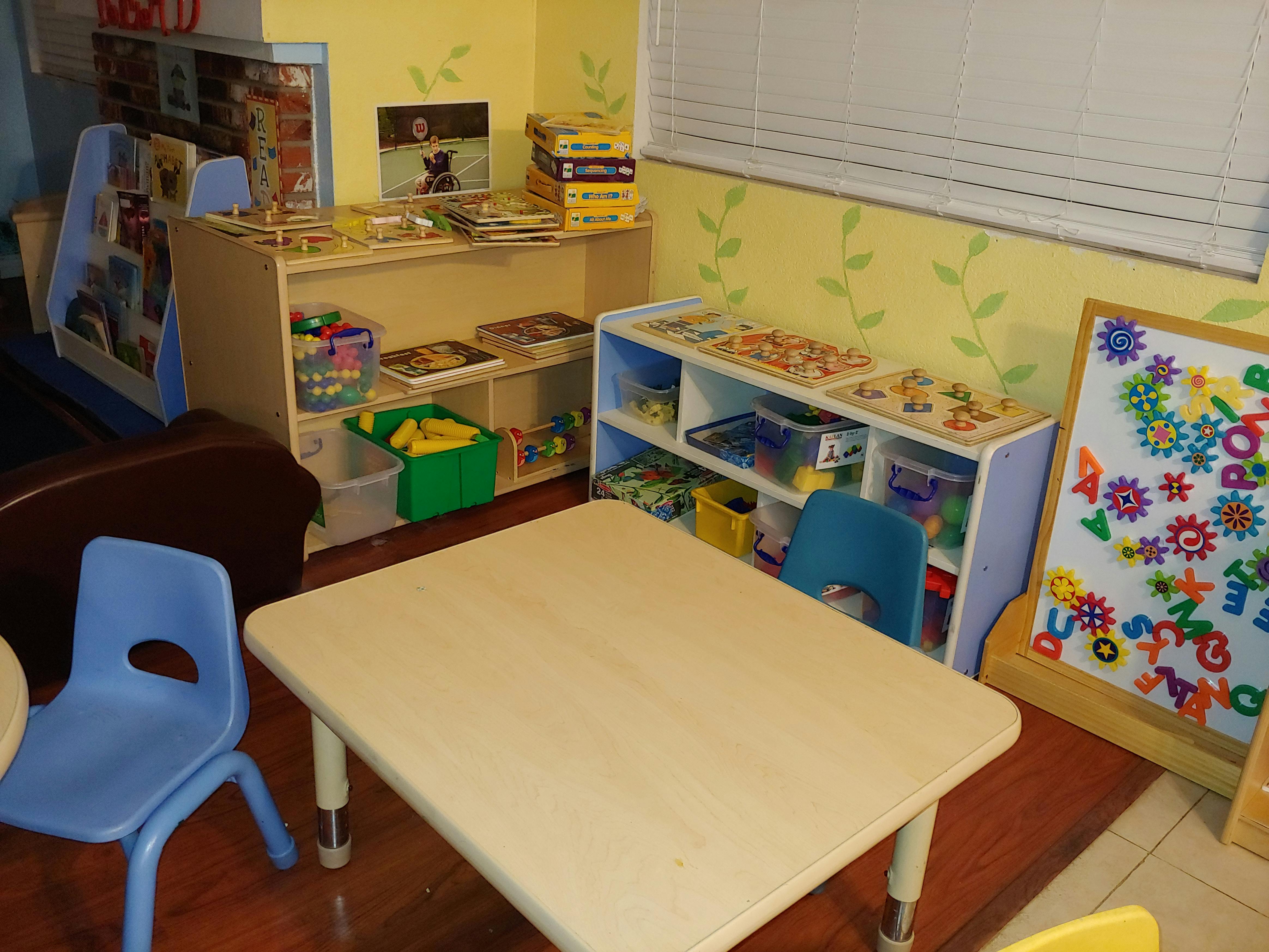 Classroom with small table and chairs, shelves with toys and books