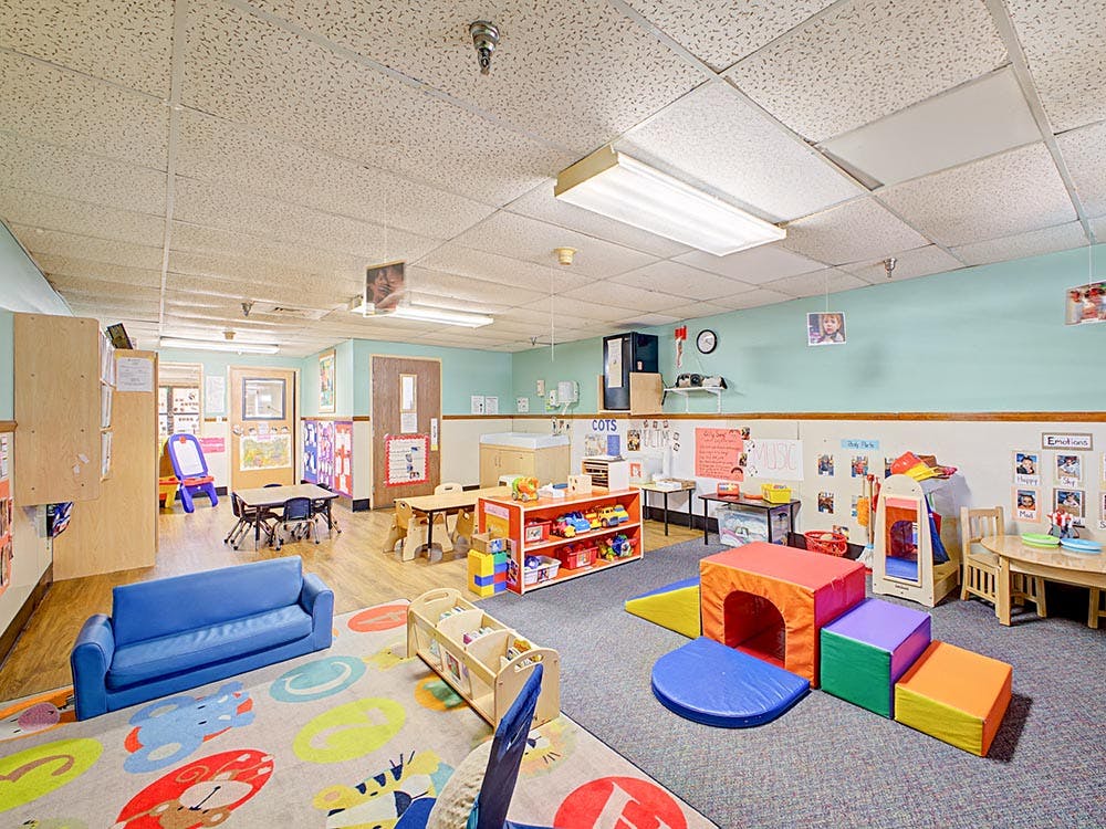 Playroom with colorful carpet, small blue couch, and play furniture