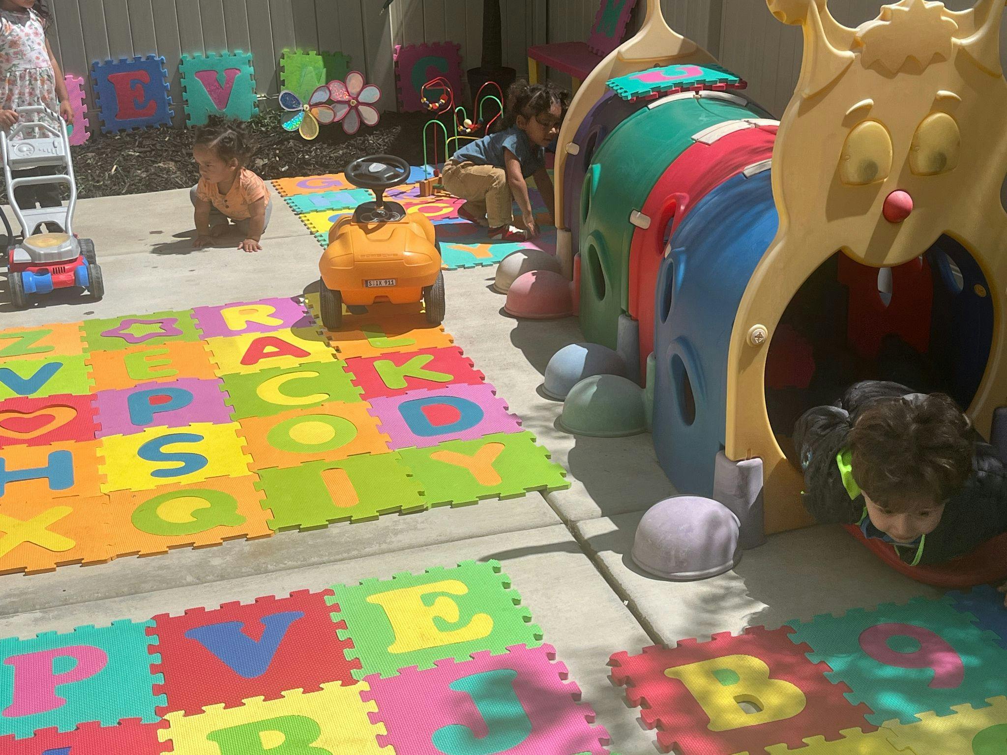 Children playing on alphabet mats and a caterpillar tunnel