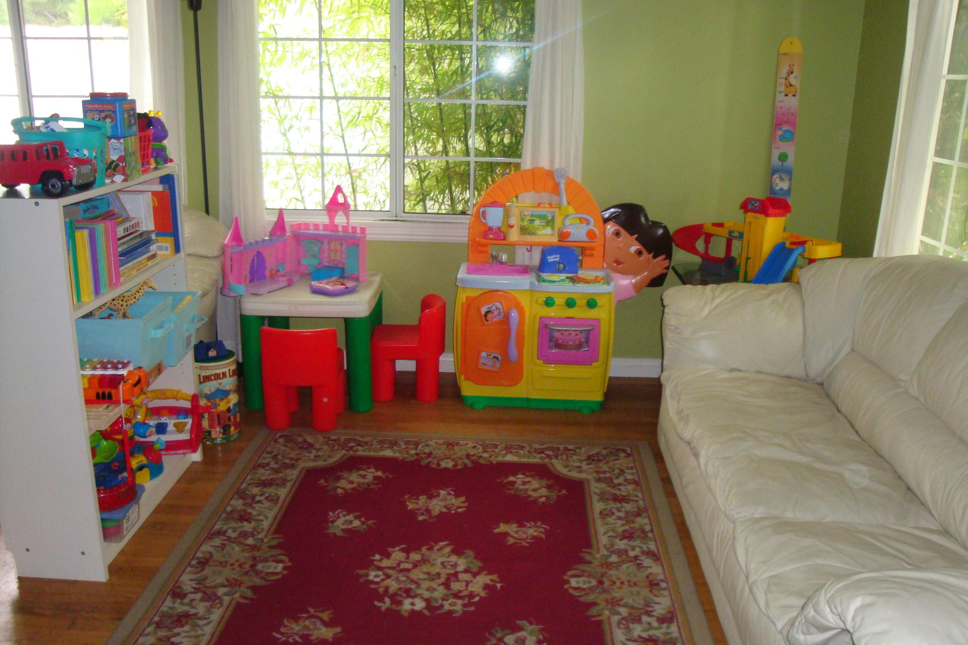 Playroom with children's furniture, shelves of toys, and a rug