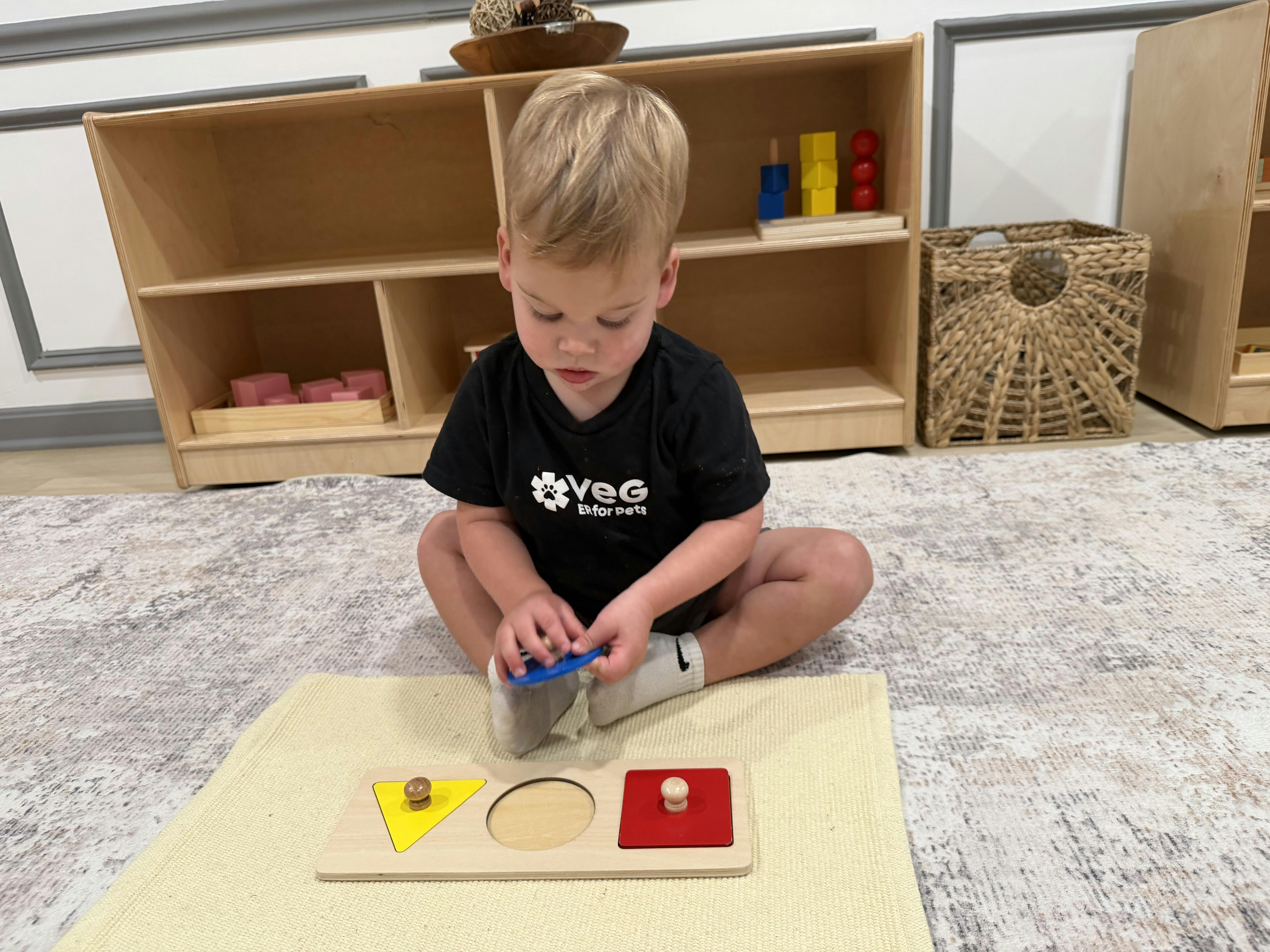 Child sitting on a rug and playing with a wooden shape sorting puzzle