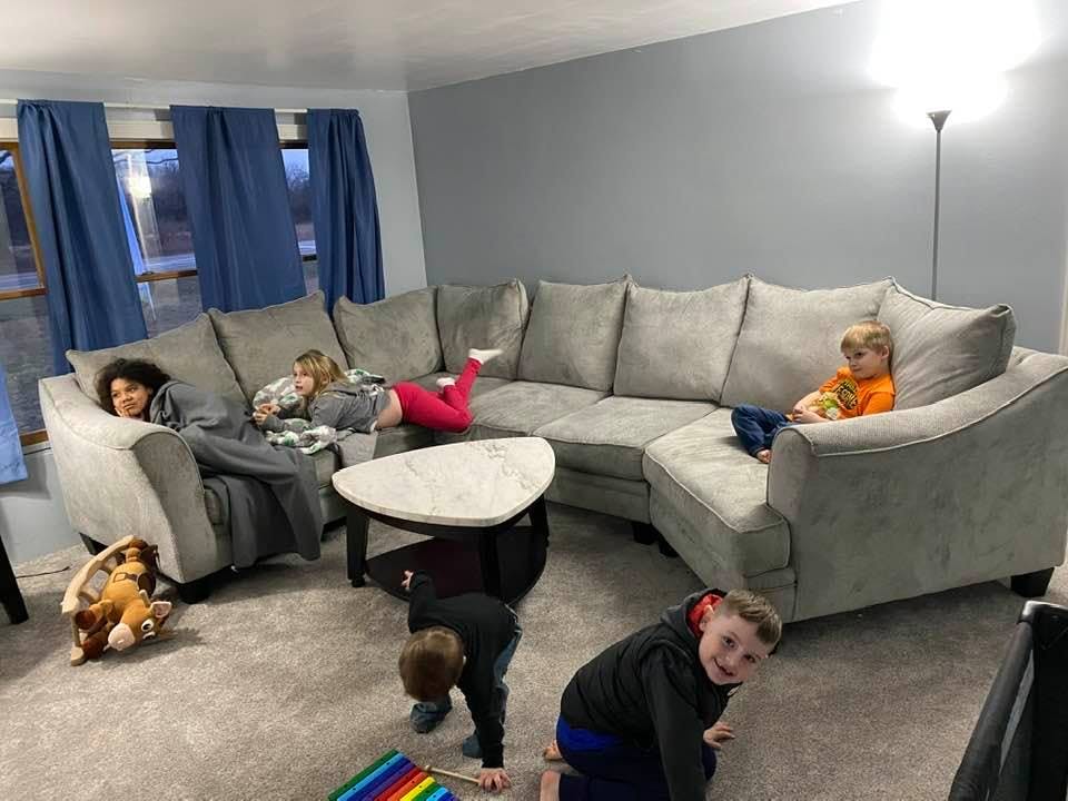 Multiple children in a living room, some on a sectional sofa, others on the floor