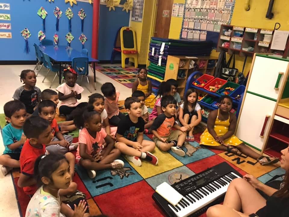 Children sitting on a colorful rug in a classroom