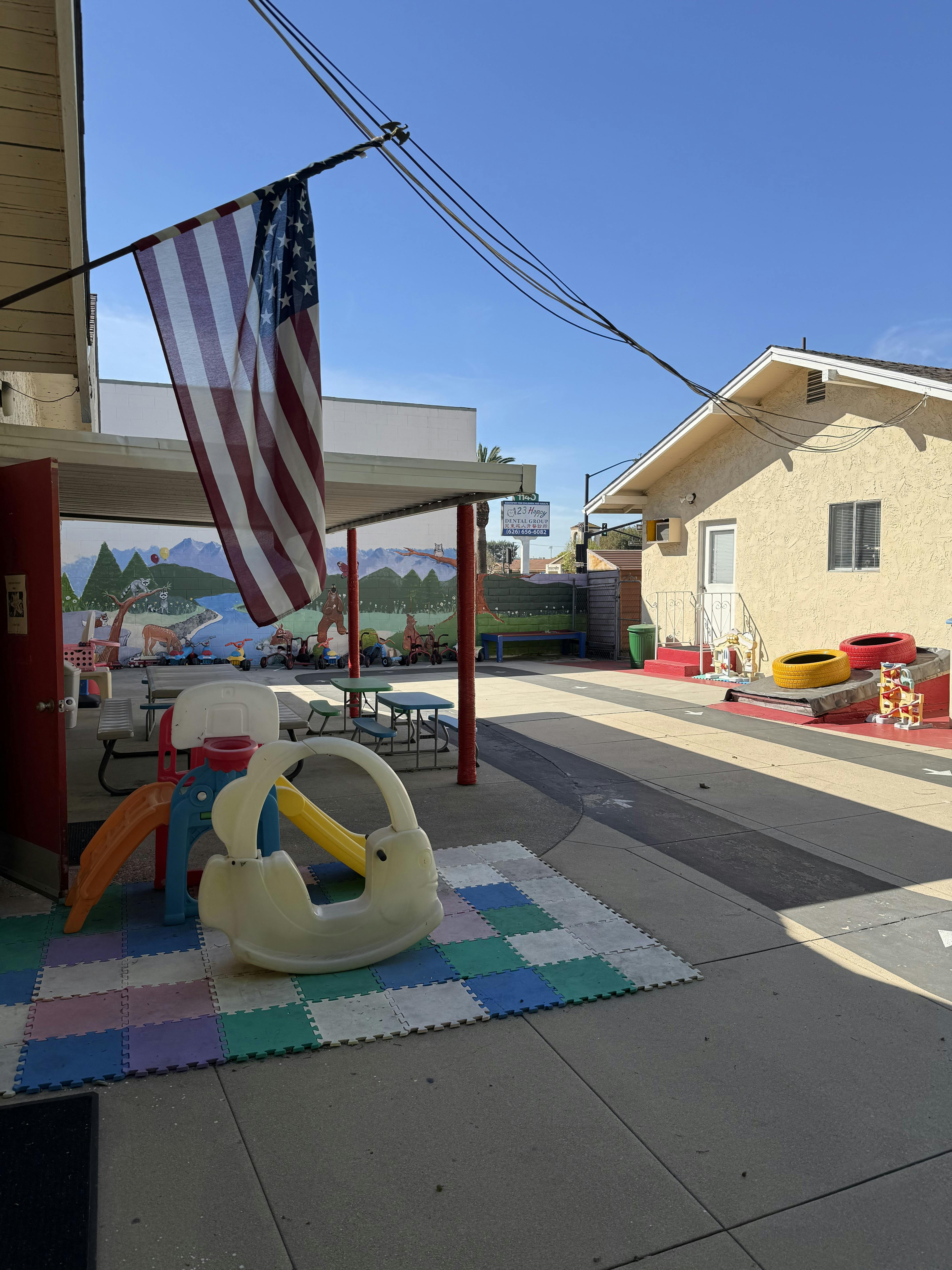 Children's playground with toys and an American flag hanging from a porch