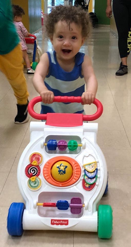 Child holding onto a Fisher-Price baby walker