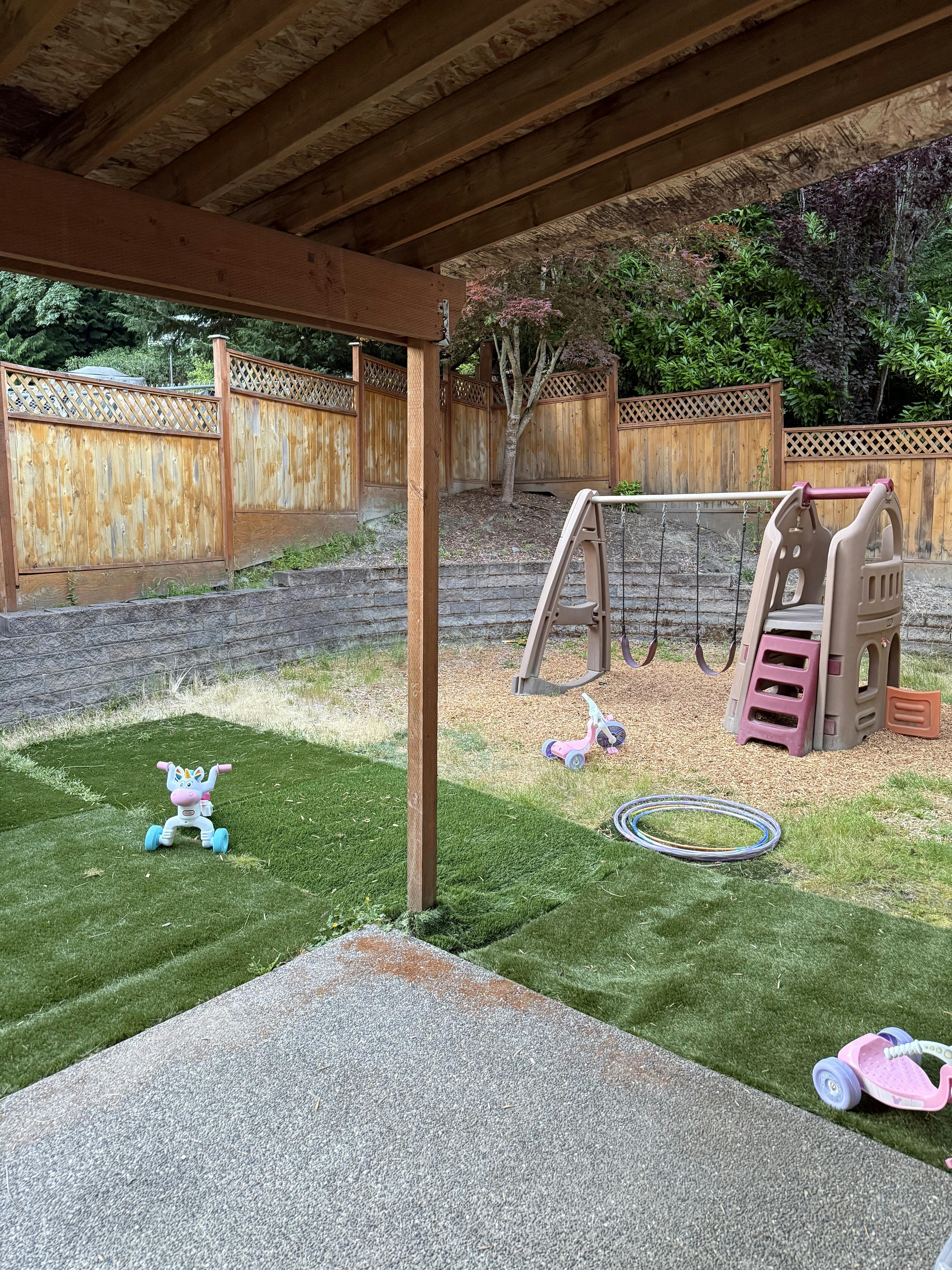 Backyard with swing set and various toys on artificial grass