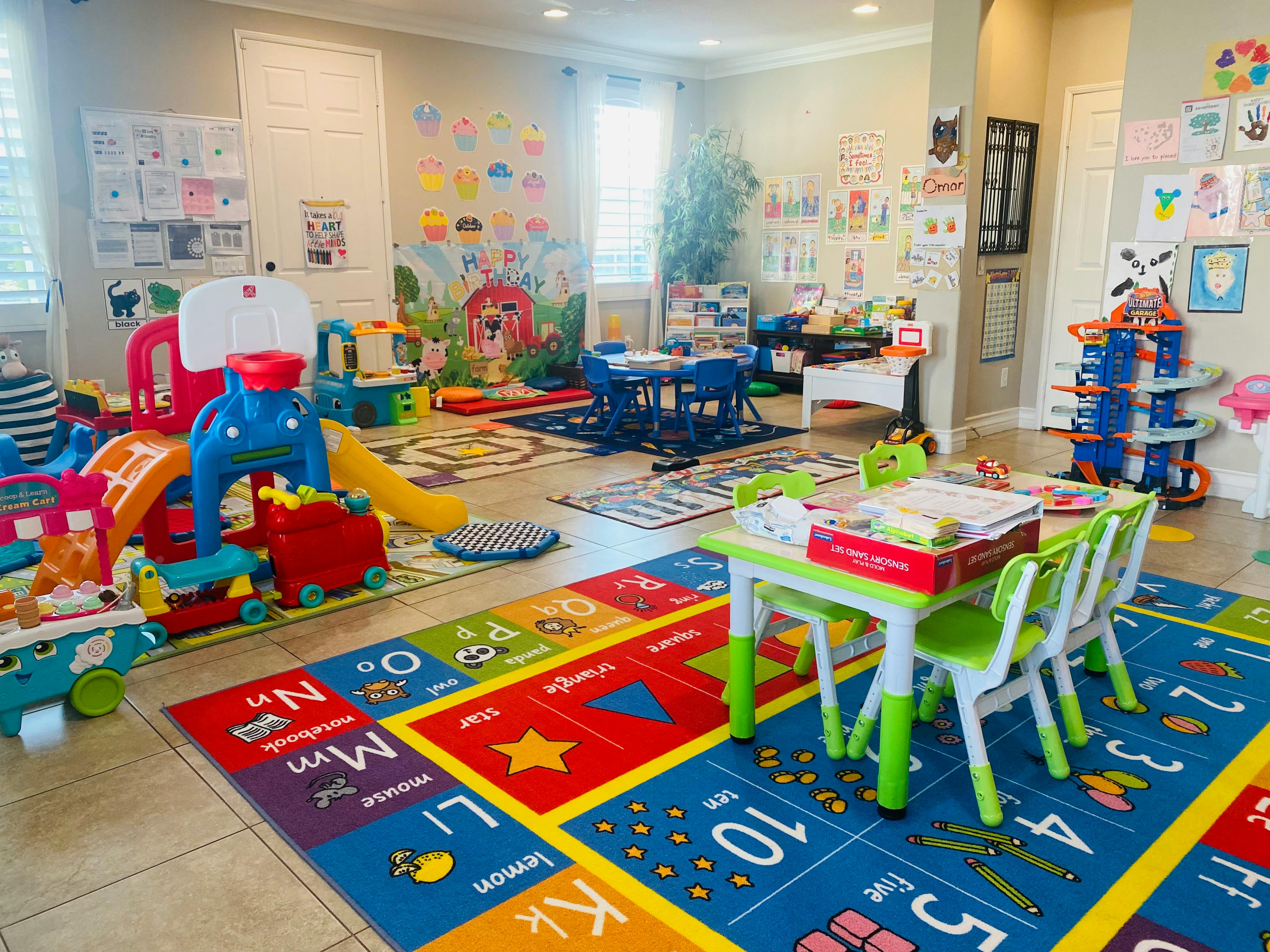 Playroom with colorful rugs, small tables and chairs, and various toys
