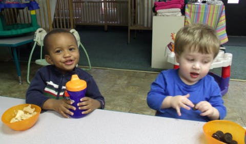 Two children sitting at a table with bowls and bowls