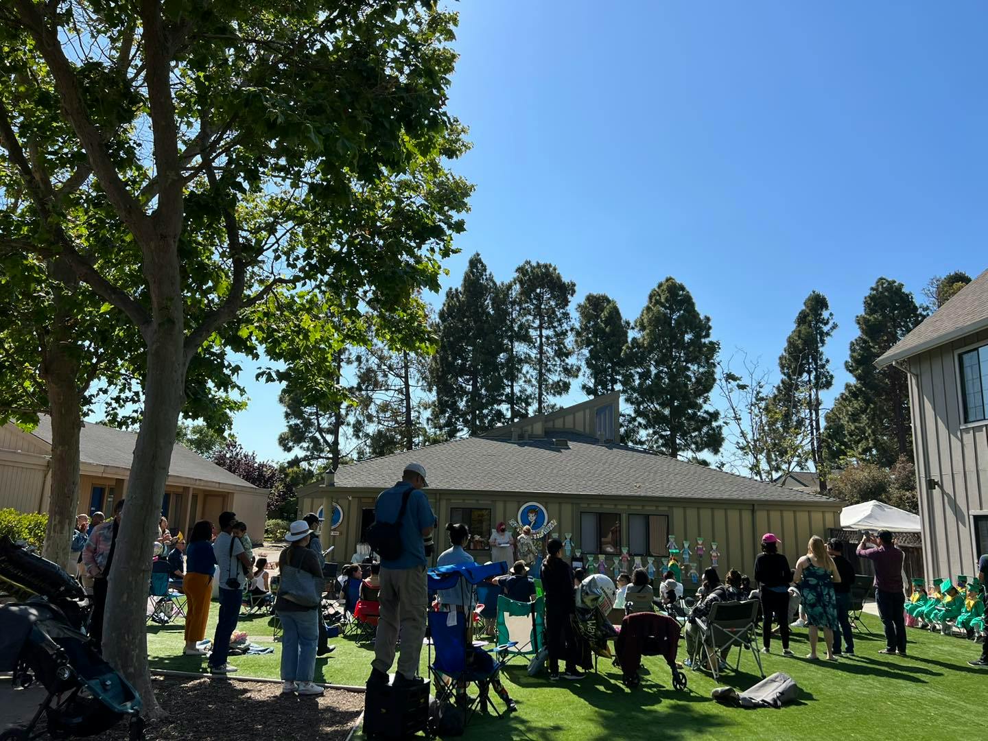 People gathered outdoors watching a performance on a grassy area