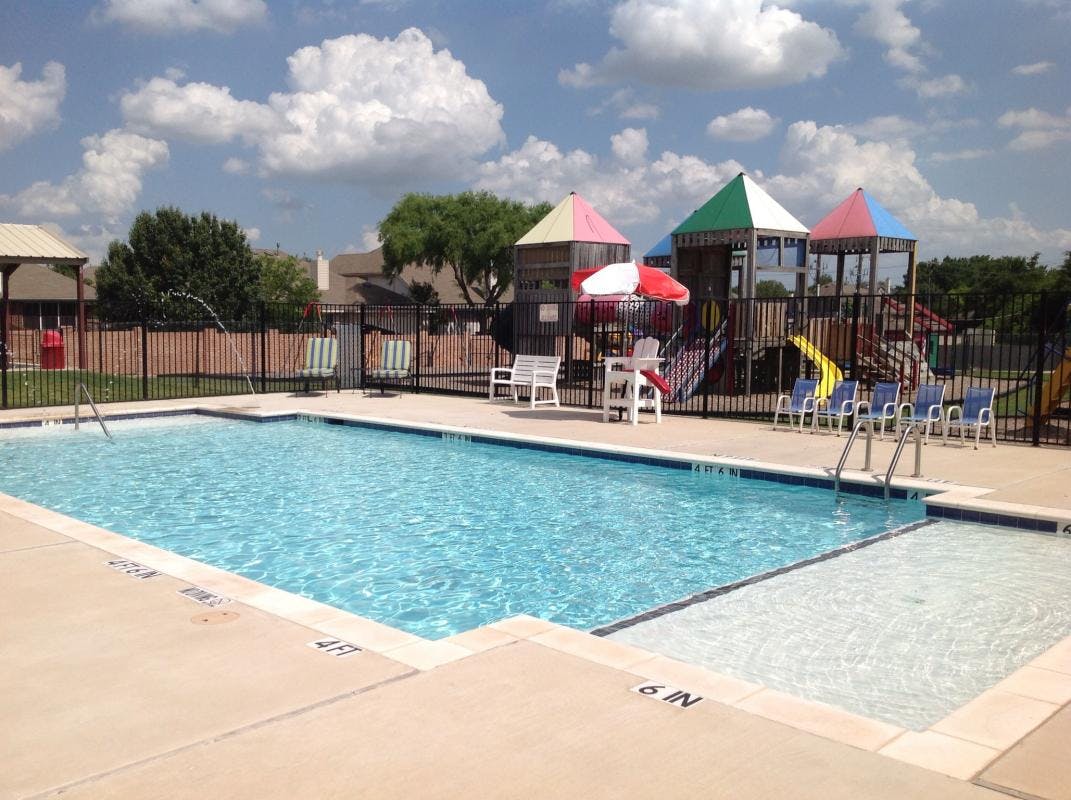 Swimming pool with a shallow entry area and a playground in the background