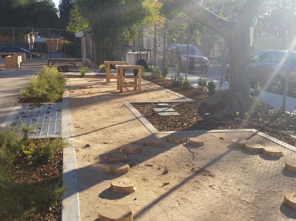 Outdoor area with dirt paths, wooden stumps, and small wooden tables