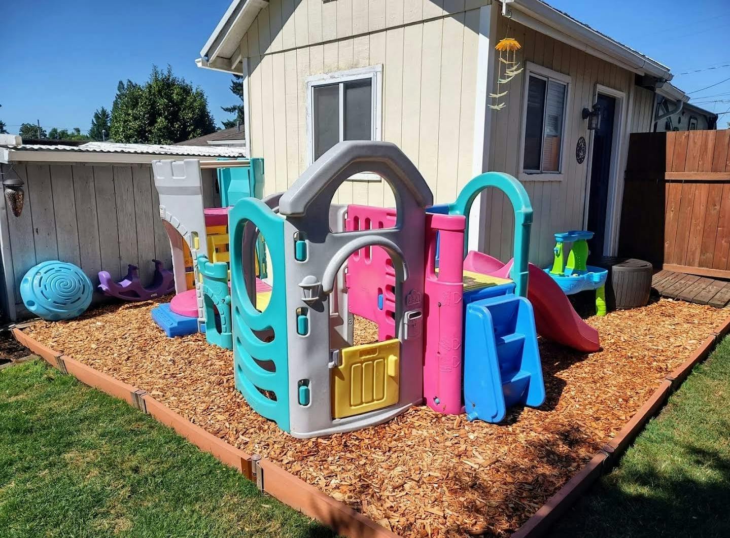 Colorful plastic playground set on wood chips in a backyard