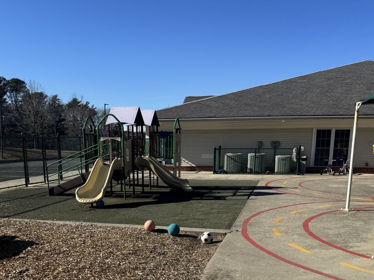 Playground structure with slides and a climbing area next to a building