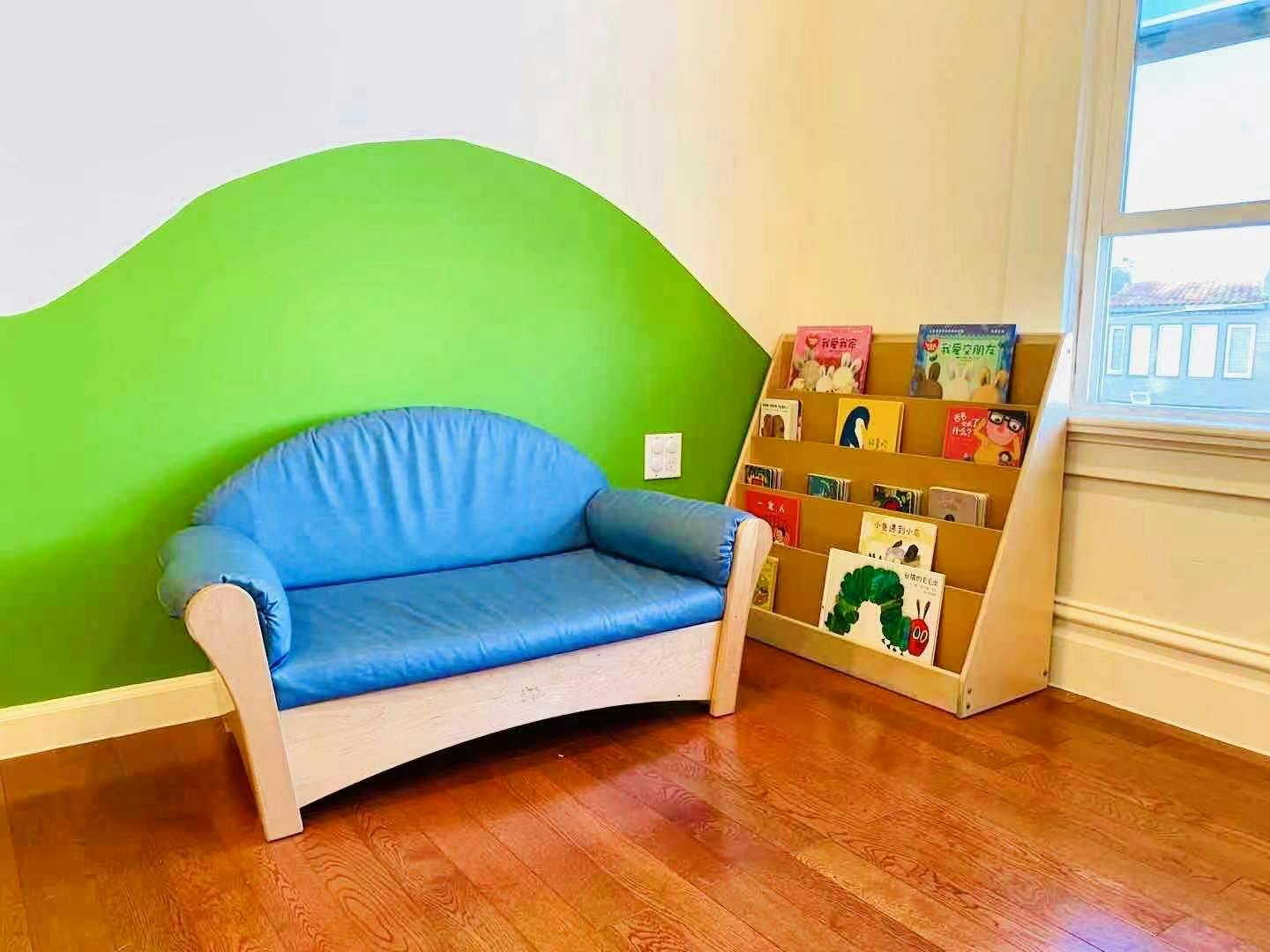 Blue child-sized sofa next to a wooden bookshelf with books