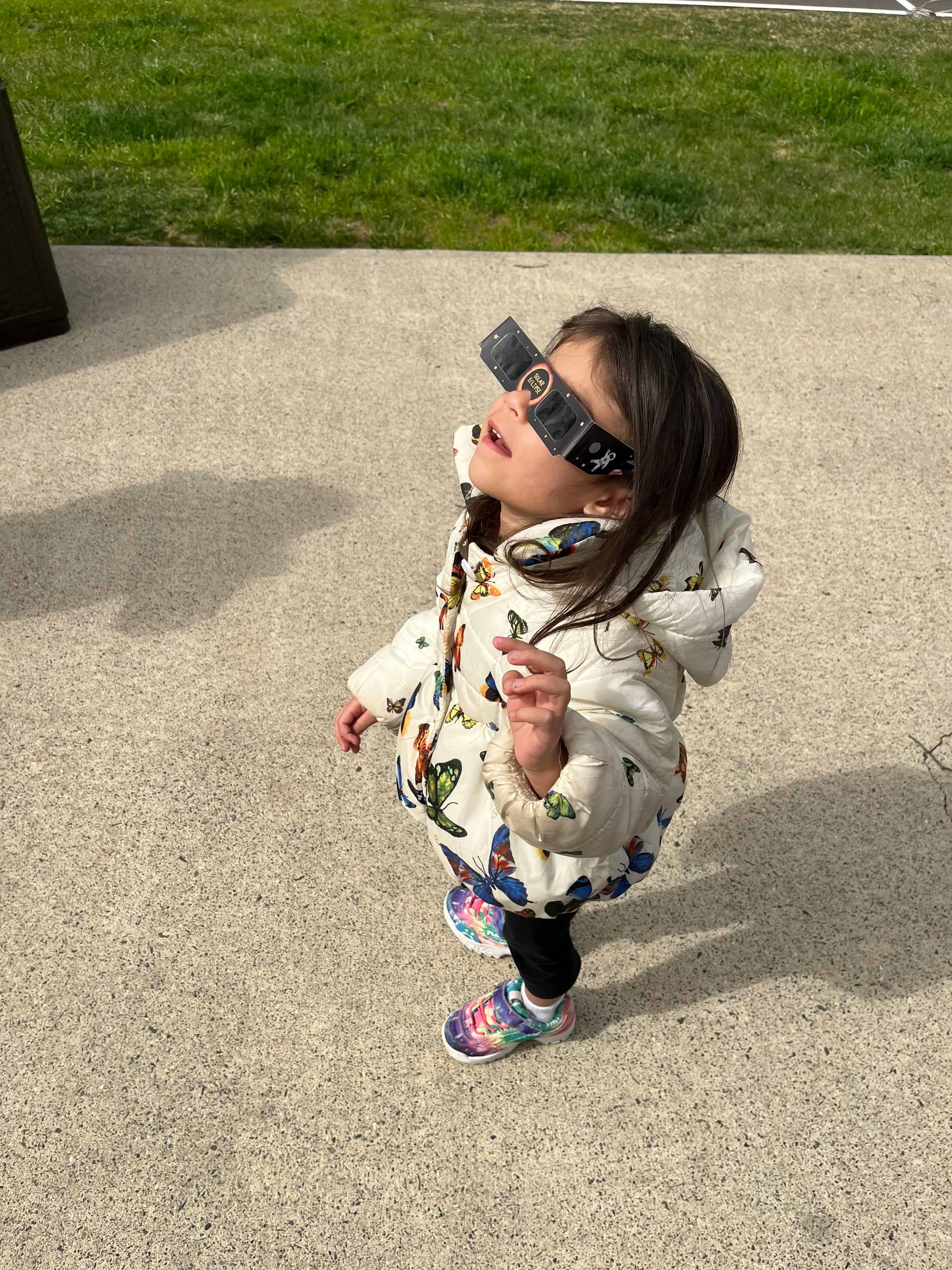 Child wearing eclipse glasses looking up