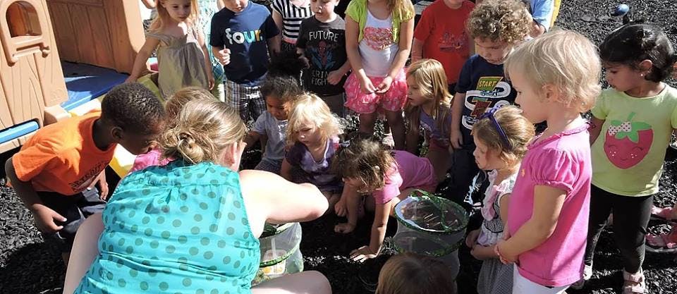 Adult and children gathered around an object on the ground