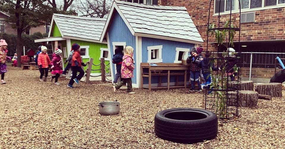 Children playing near small playhouses in a yard