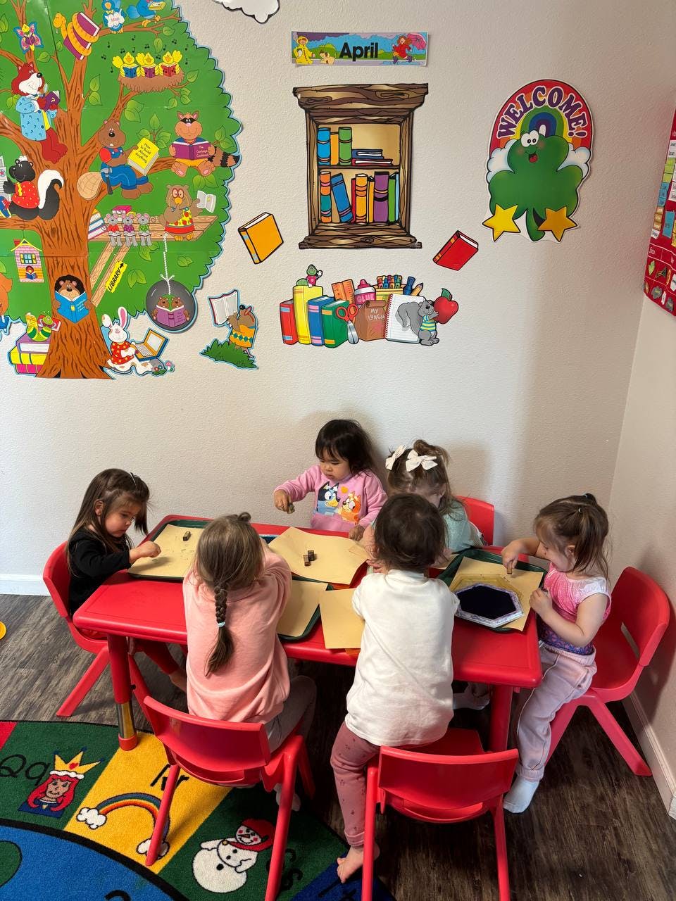 Children sitting at a red table doing crafts in-class activities