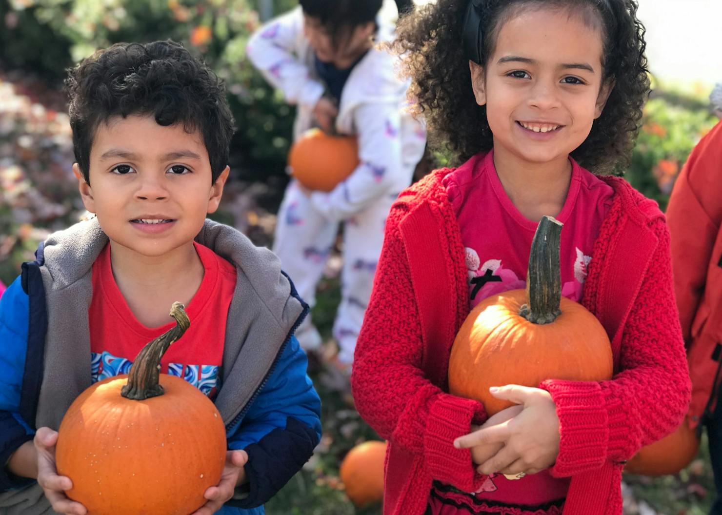 Two children holding pumpkins