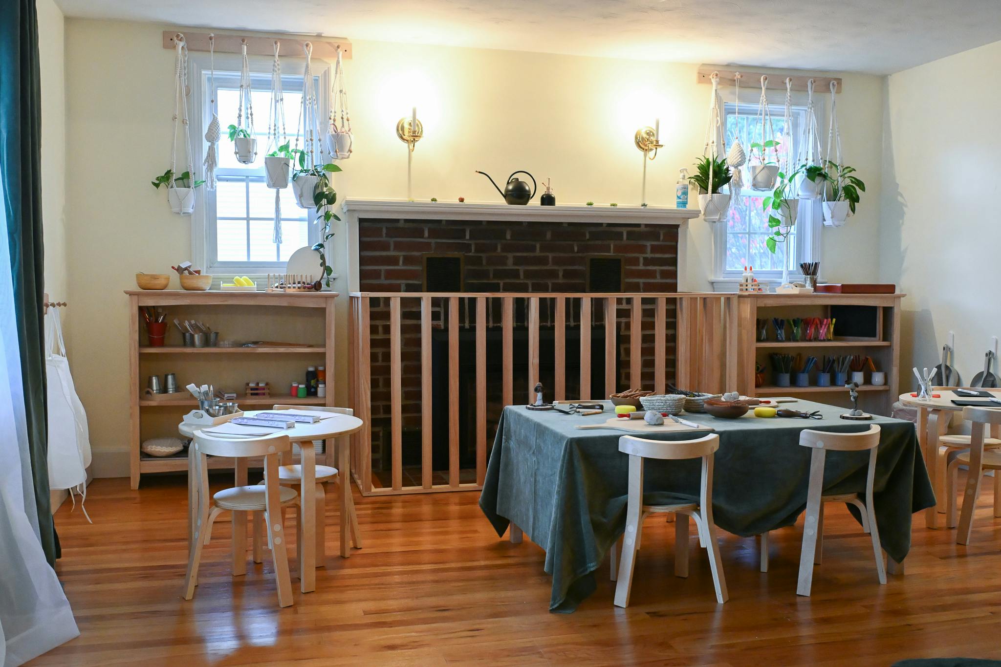 Children's classroom with small tables and chairs, shelves, and fireplace with barrier