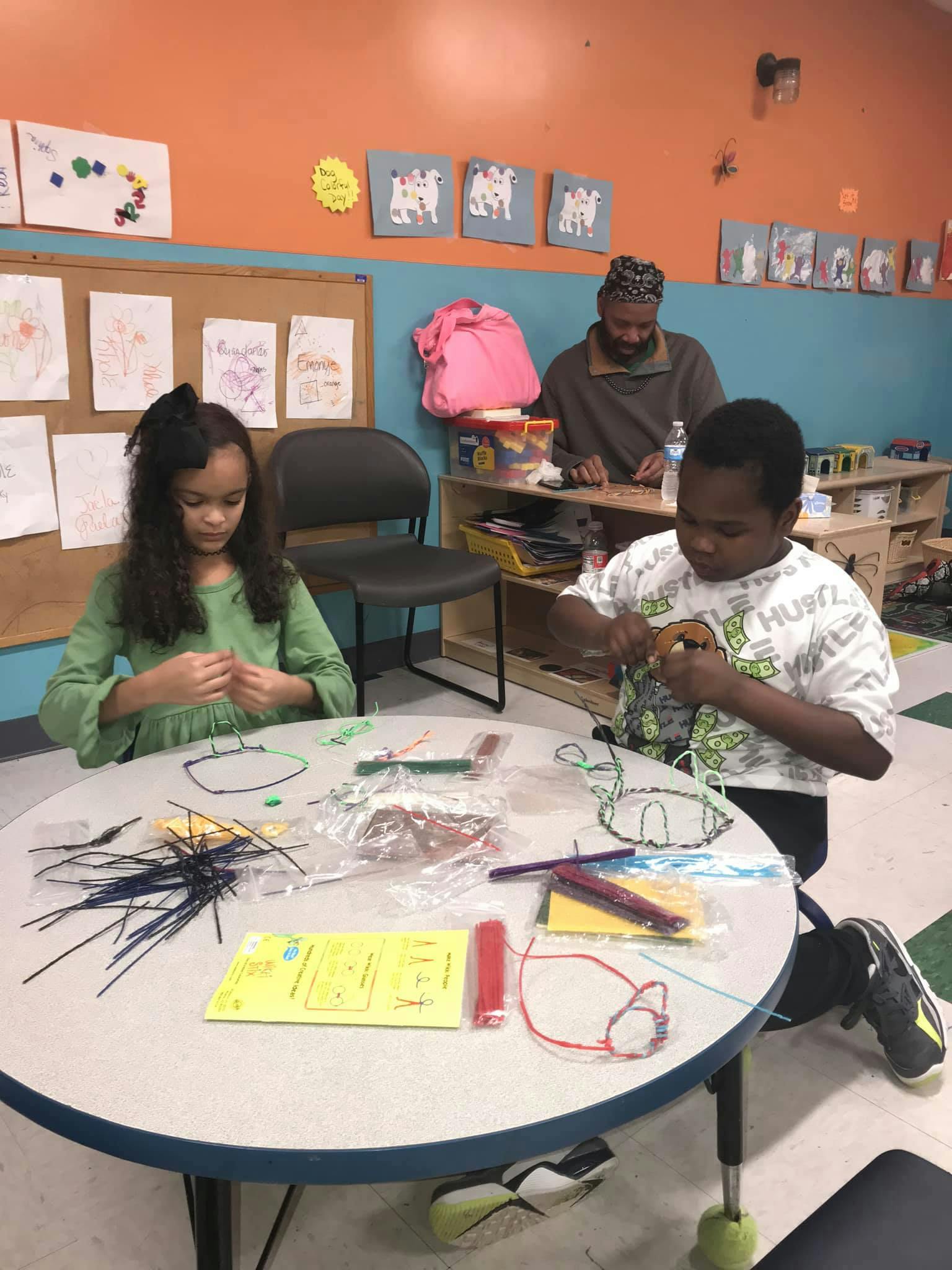 Two children and an adult making crafts at a table