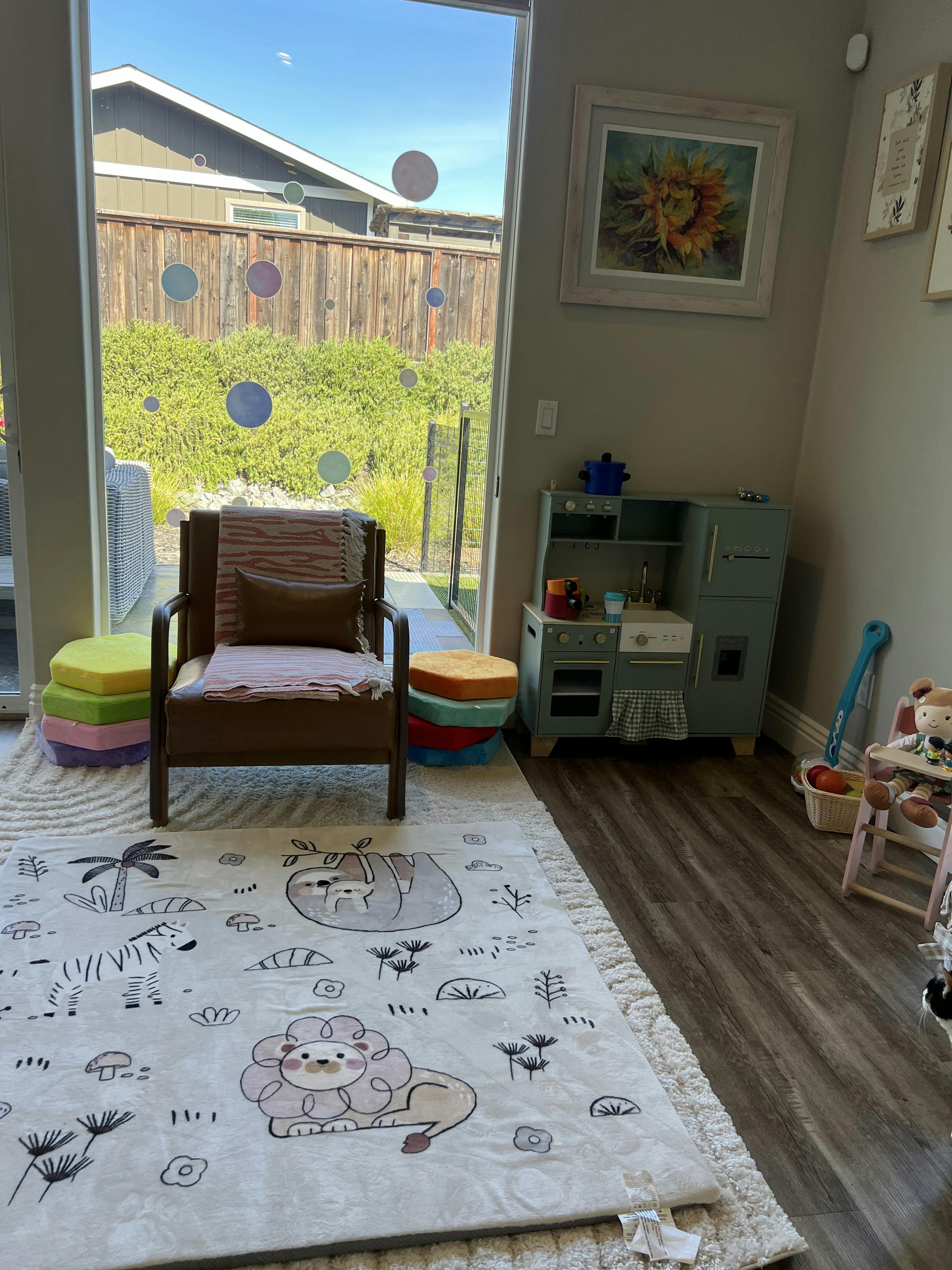 Playroom with children's kitchen set, an armchair, and a rug with animal designs