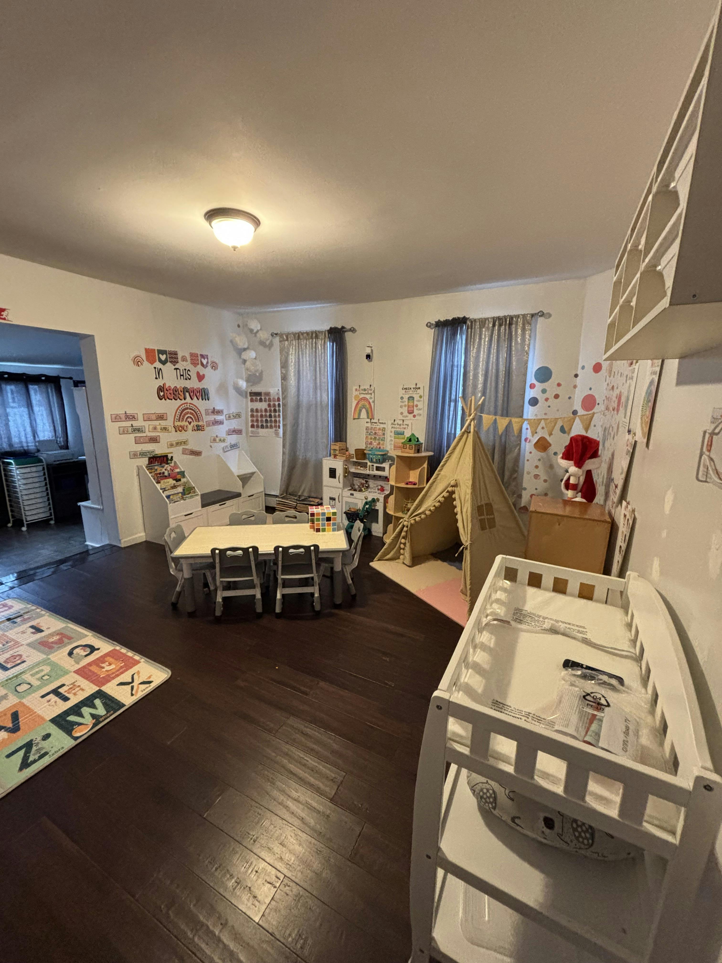 Classroom with a table and chairs, teepee, changing table, and decorative wall art