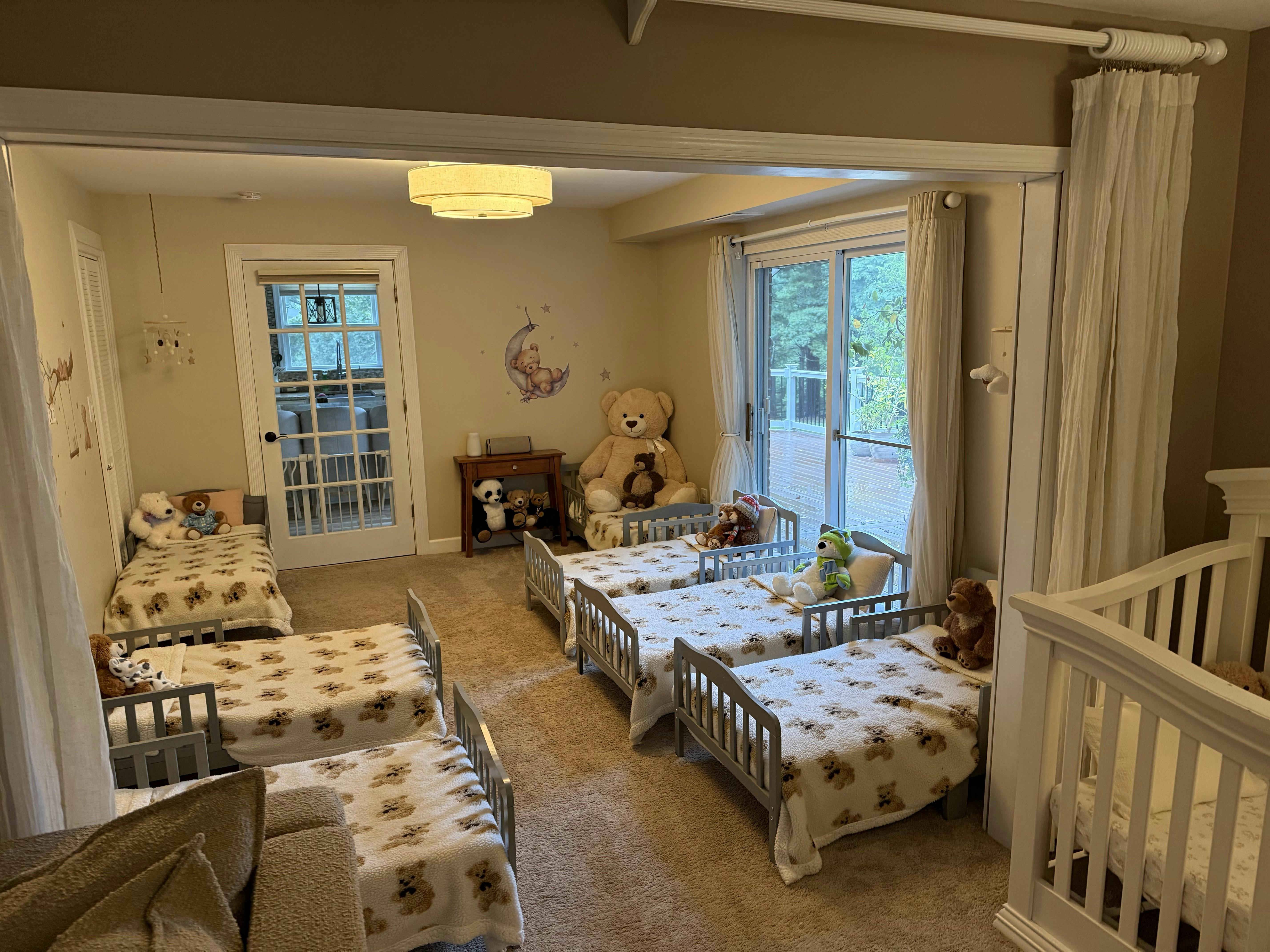 Multiple small beds with bear-patterned blankets arranged in a nursery room