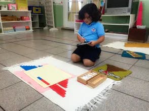 Child kneeling and writing on a clipboard
