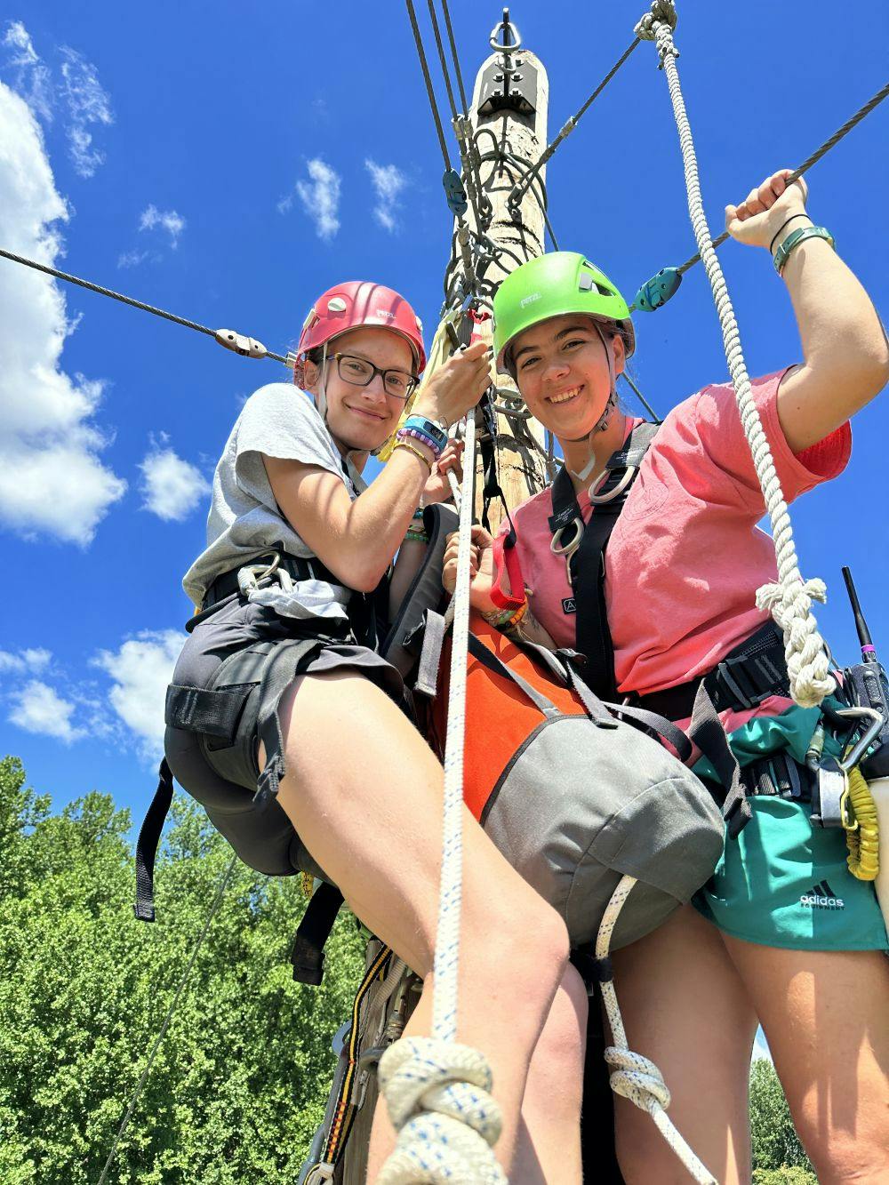 Two teens in helmets and harnesses on a ropes course