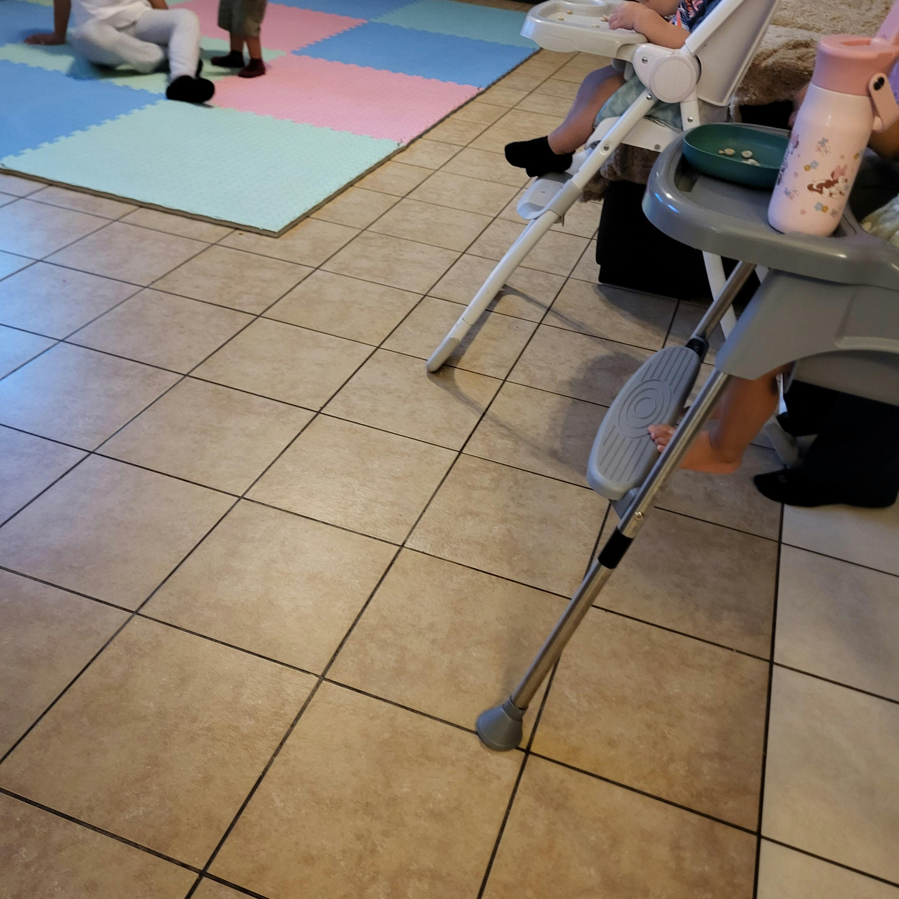 Child sitting in a high chair with a snack bowl and water bottle