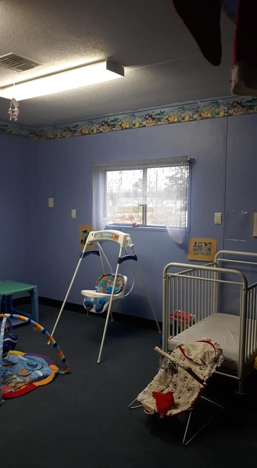 Nursery room with a crib, baby swing, and play mat