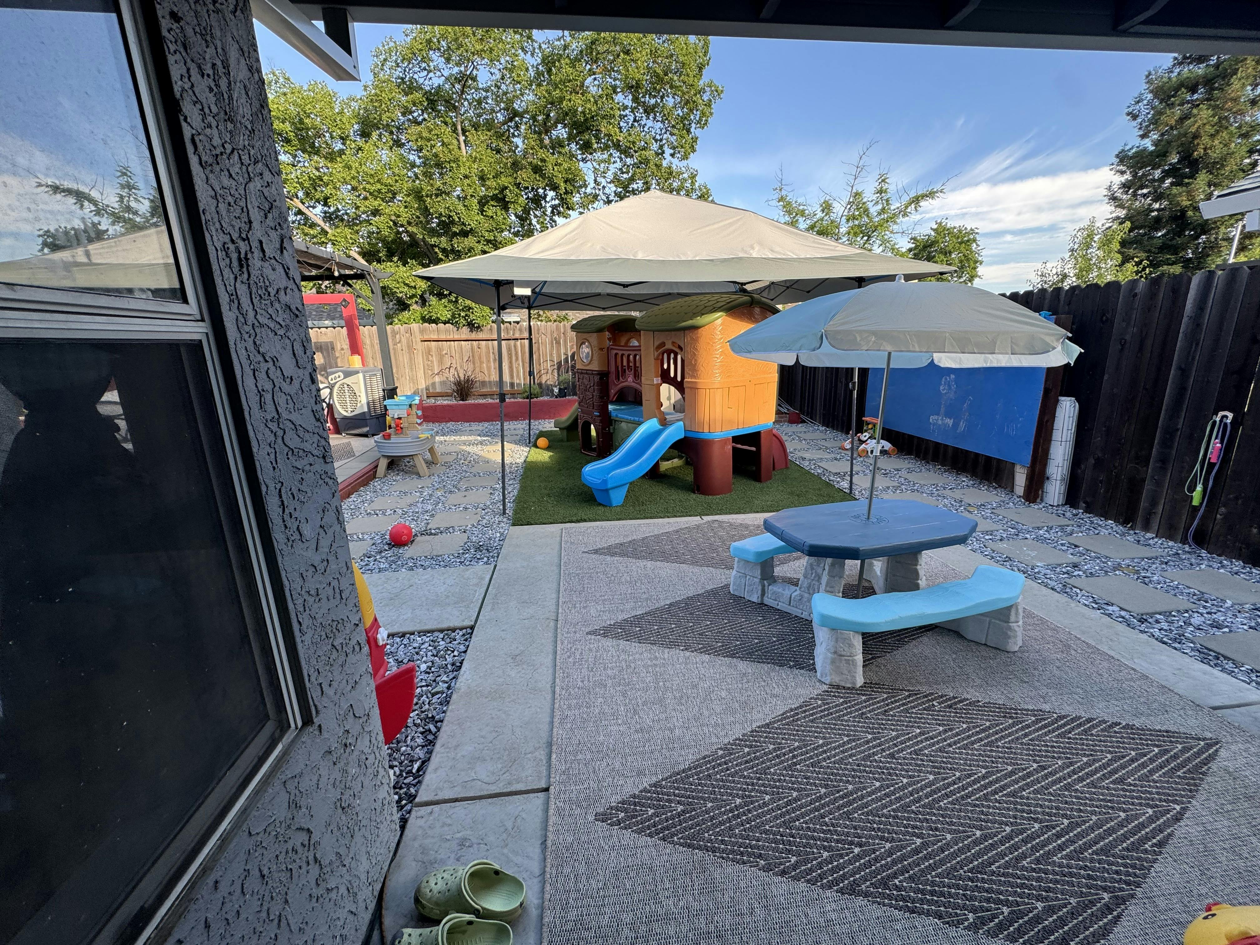 Outdoor play area with a play structure, slide, and picnic table