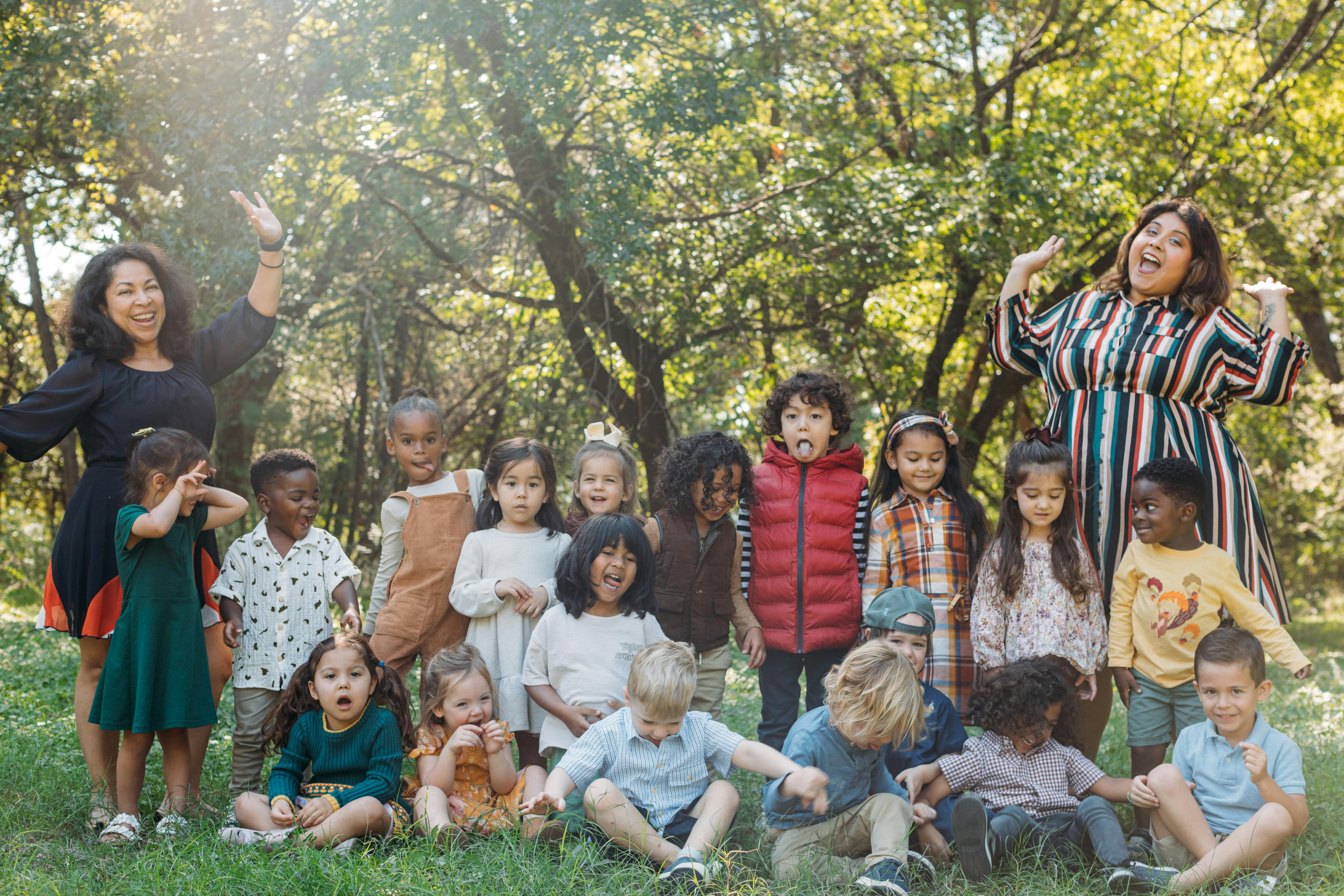 Two adults and a group of children posing outdoors