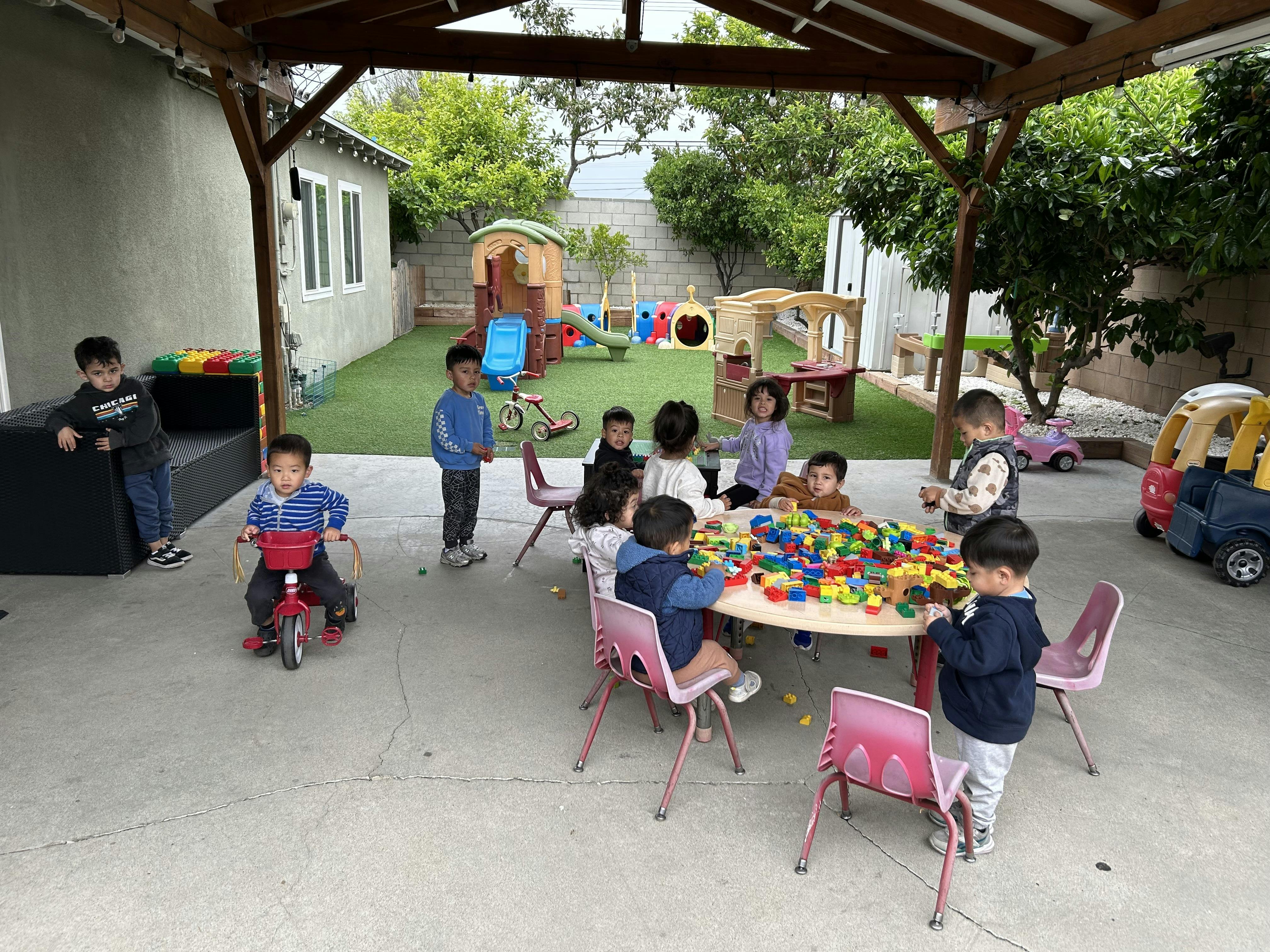 Group of children playing with building blocks at a table in a backyard