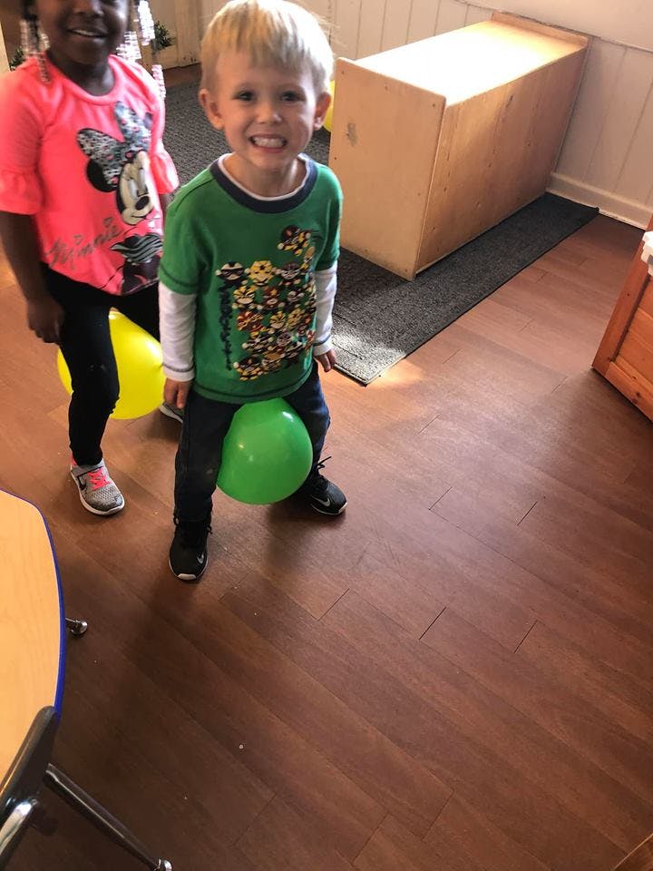 Two children playing with balloons between their legs