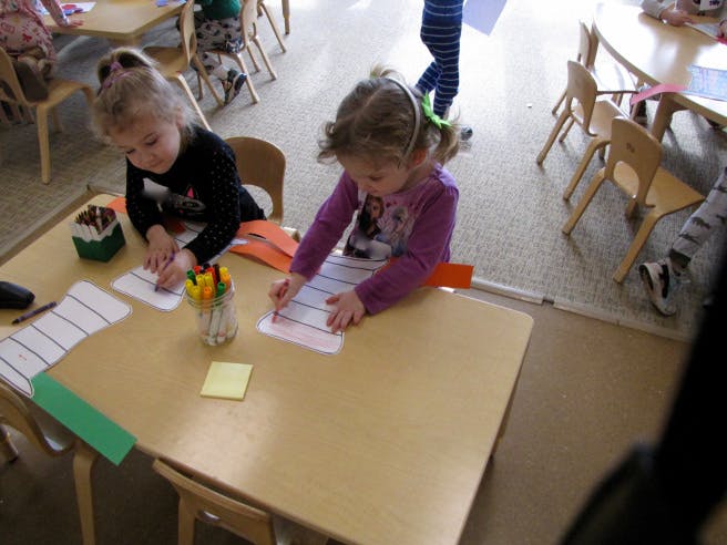 Two children drawing at a table in a classroom