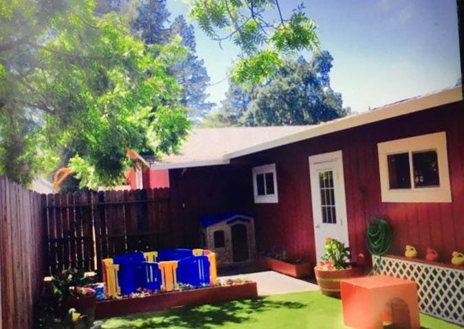 Backyard with a red building, play area, and green turf