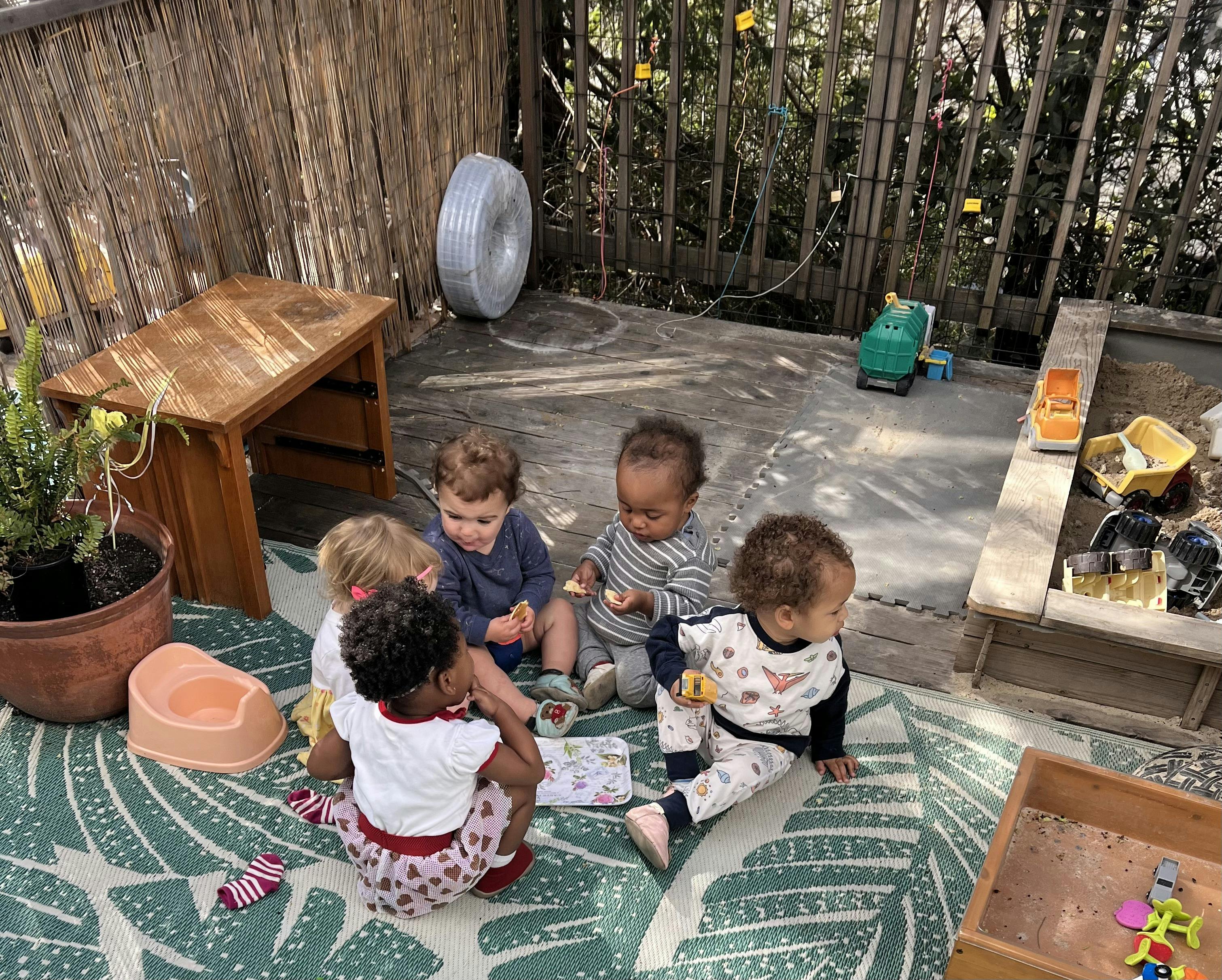 Group of children sitting on a rug playing with toys