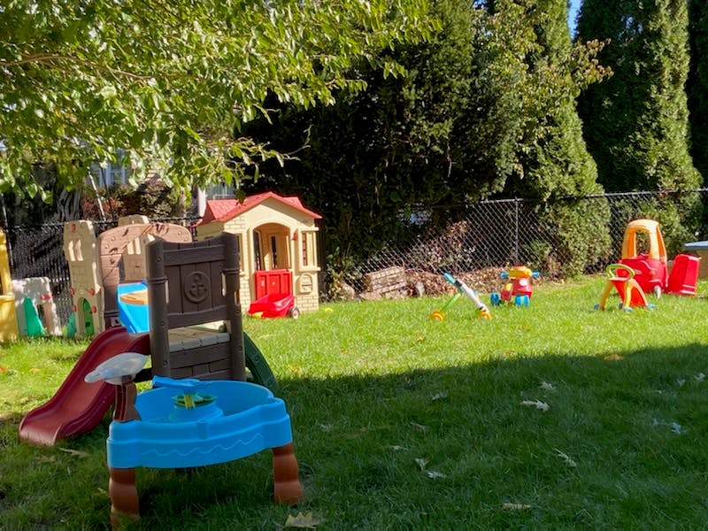 Outdoor playground with various toys and playhouses on a grassy area