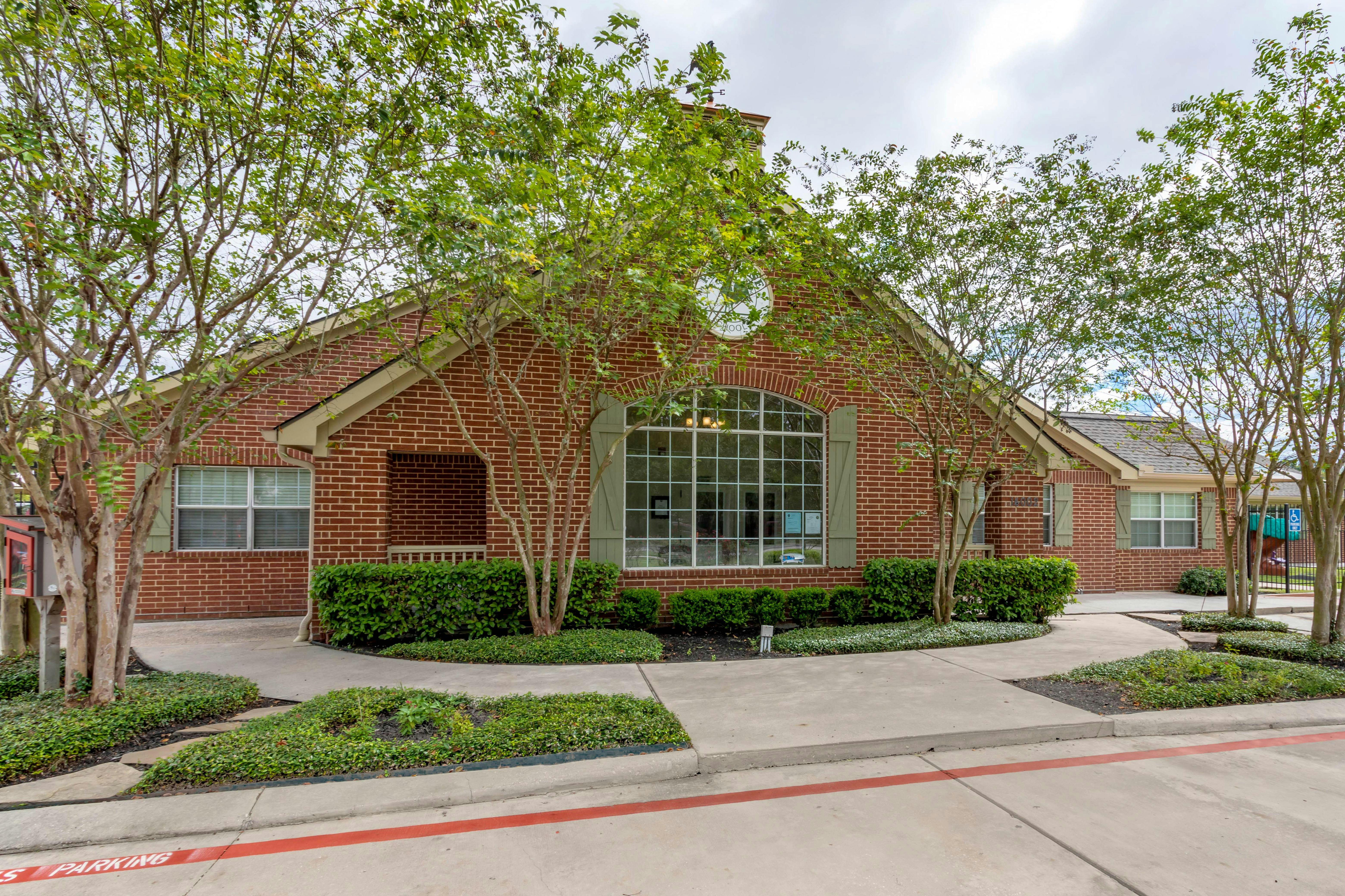 Brick building with large arched window, green shutters, and landscaping