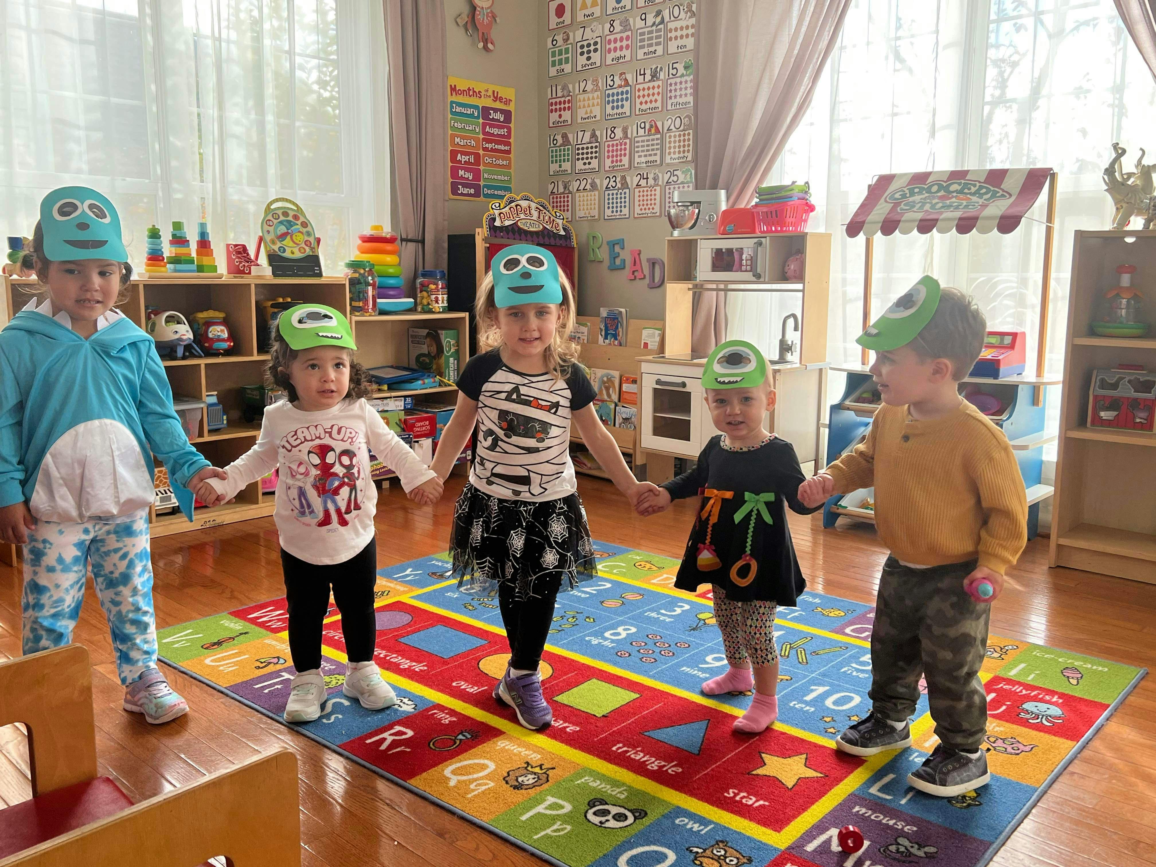 Four children wearing masks and holding hands in a classroom