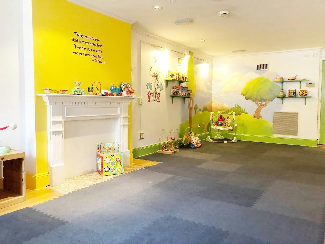 Playroom with yellow and white walls, a white fireplace, and wall murals