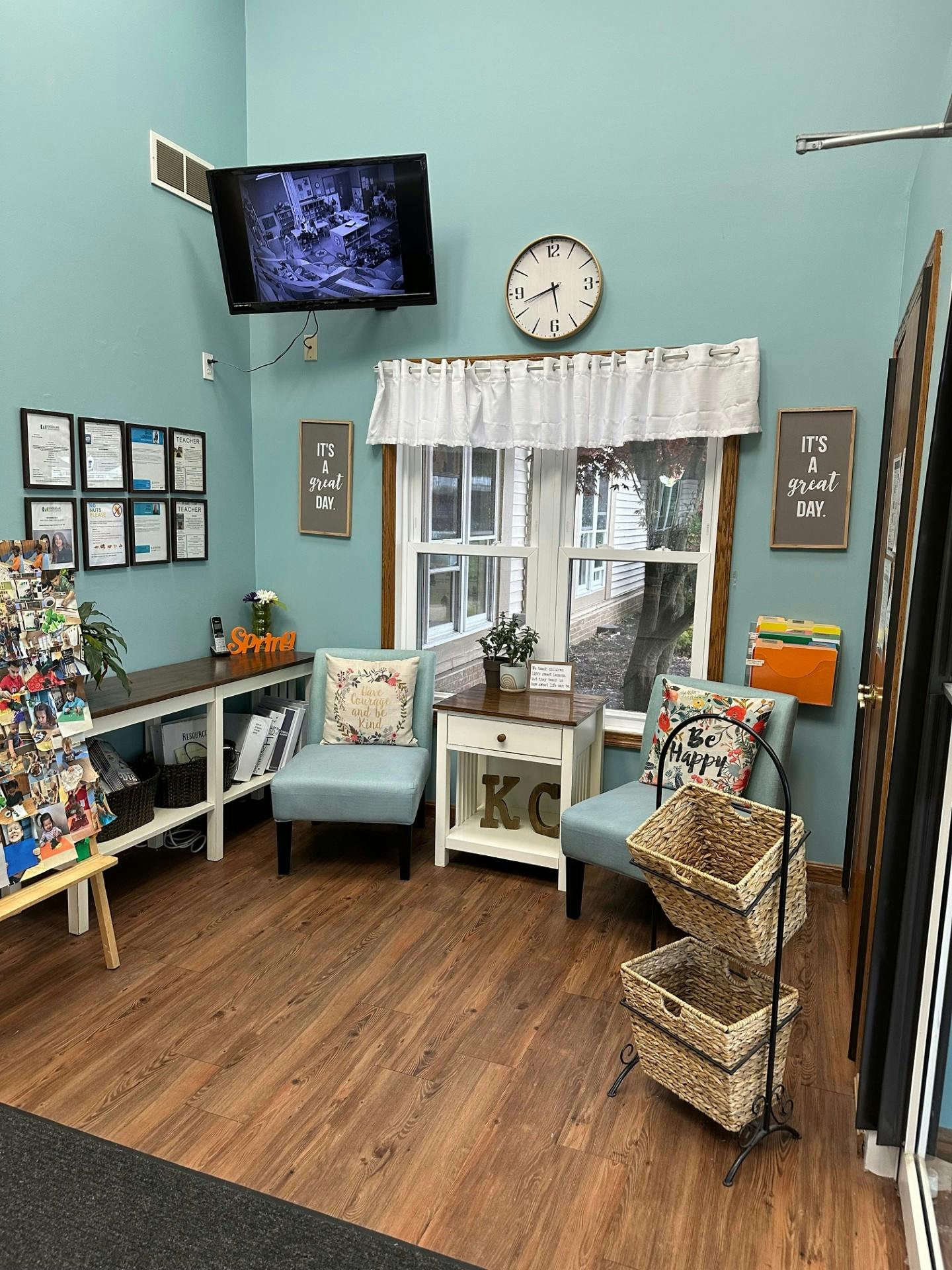 Waiting room with two chairs, wall-mounted TV, window, and wall decor