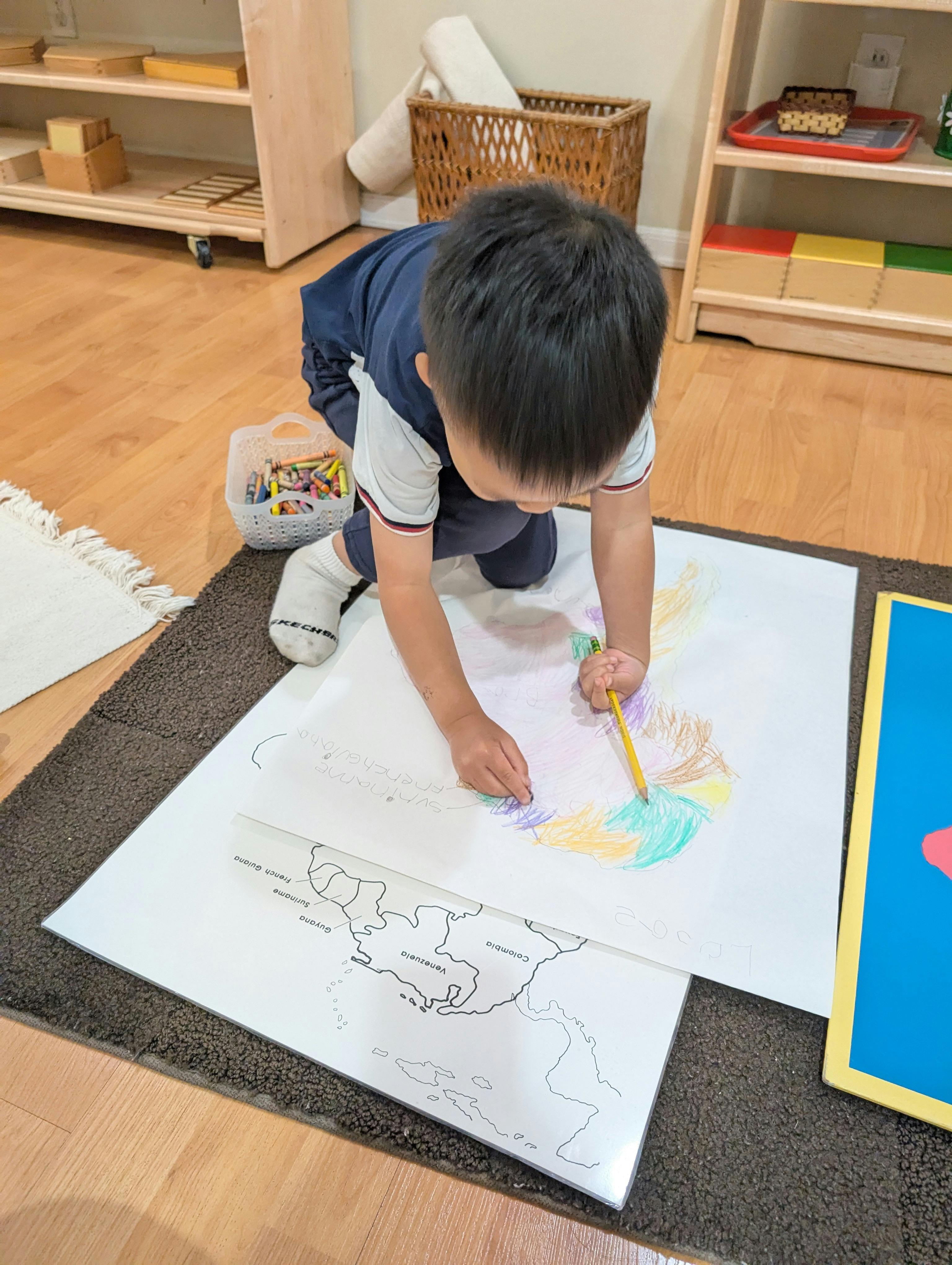 Child coloring a map on the floor