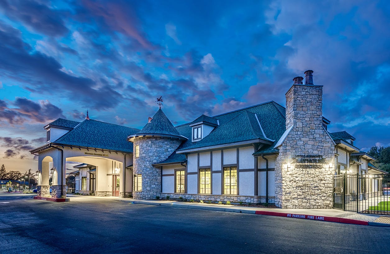 Large building with stone and white siding, arched entrance, and turret