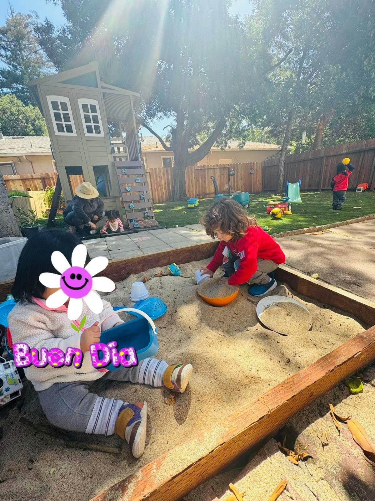 Children playing in a sandbox with an adult nearby
